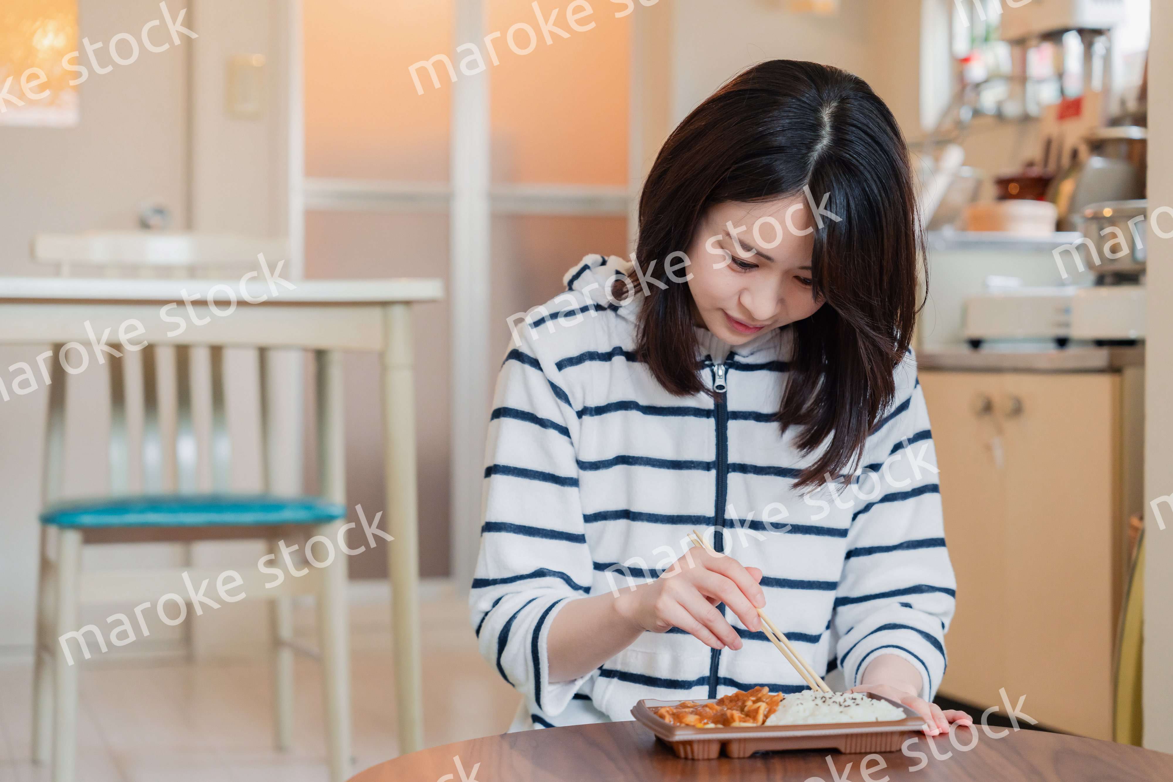 家でひとりでコンビニ弁当を食べる若い女性