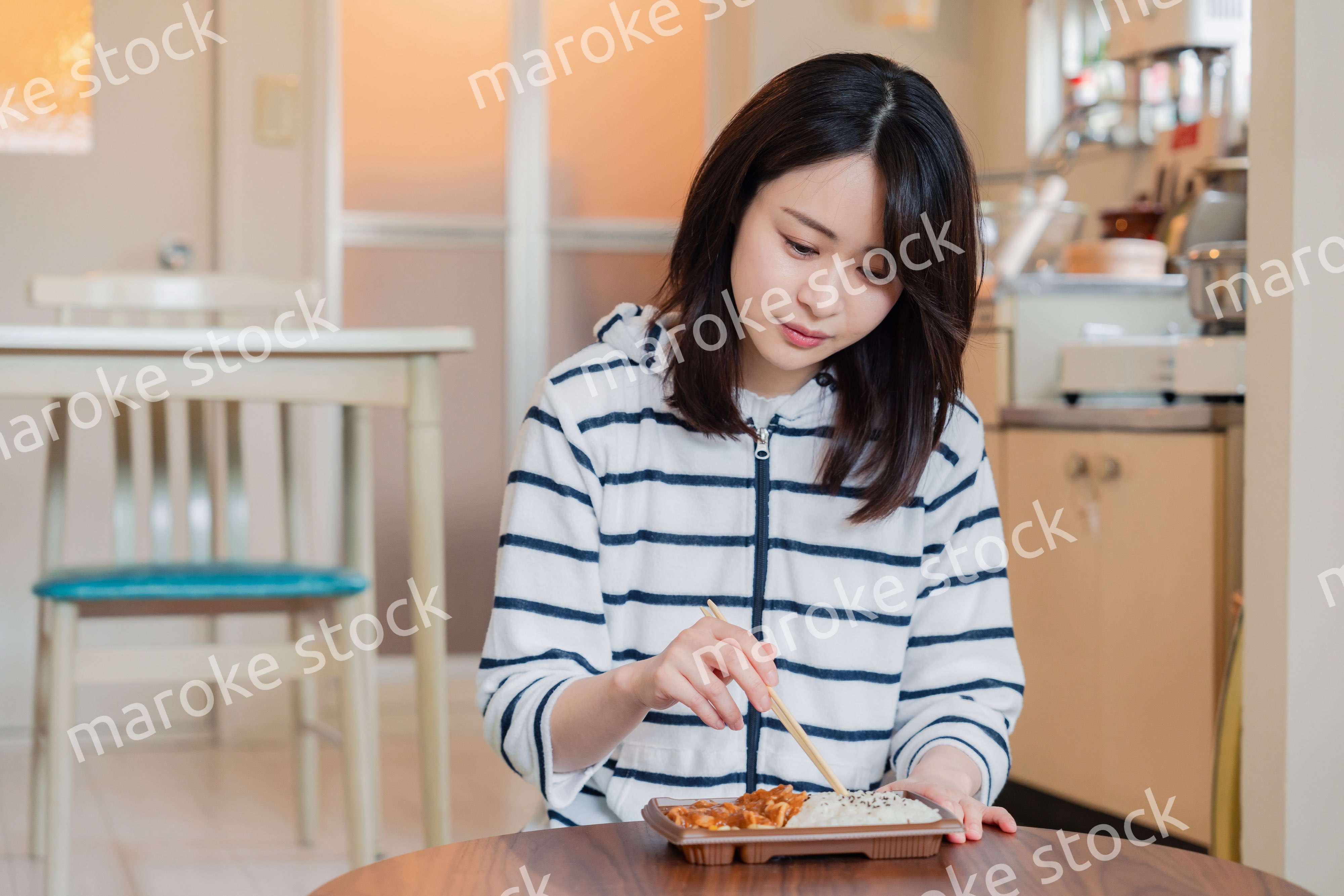 家でひとりでコンビニ弁当を食べる若い女性