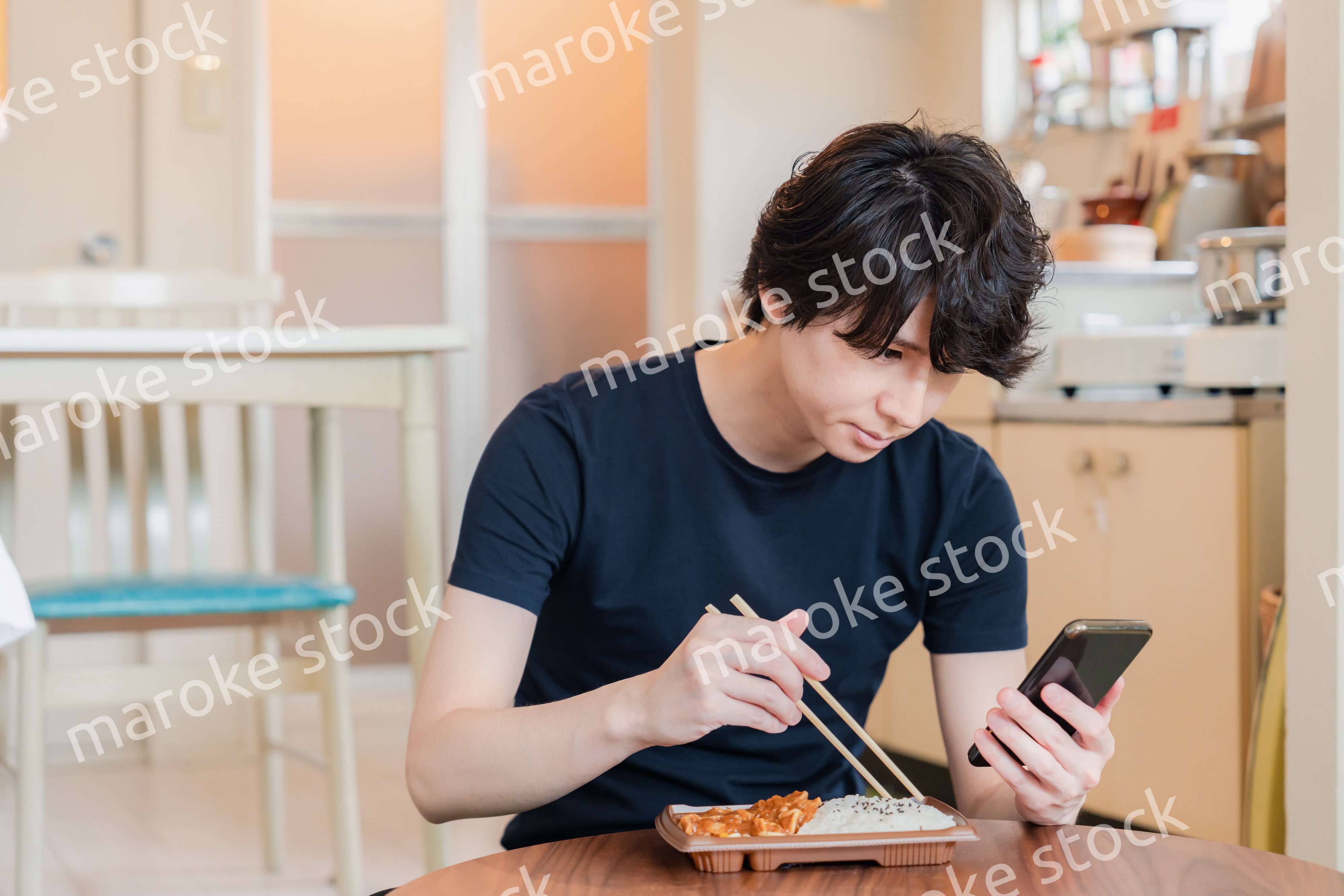 家でコンビニ弁当を食べる若い男性