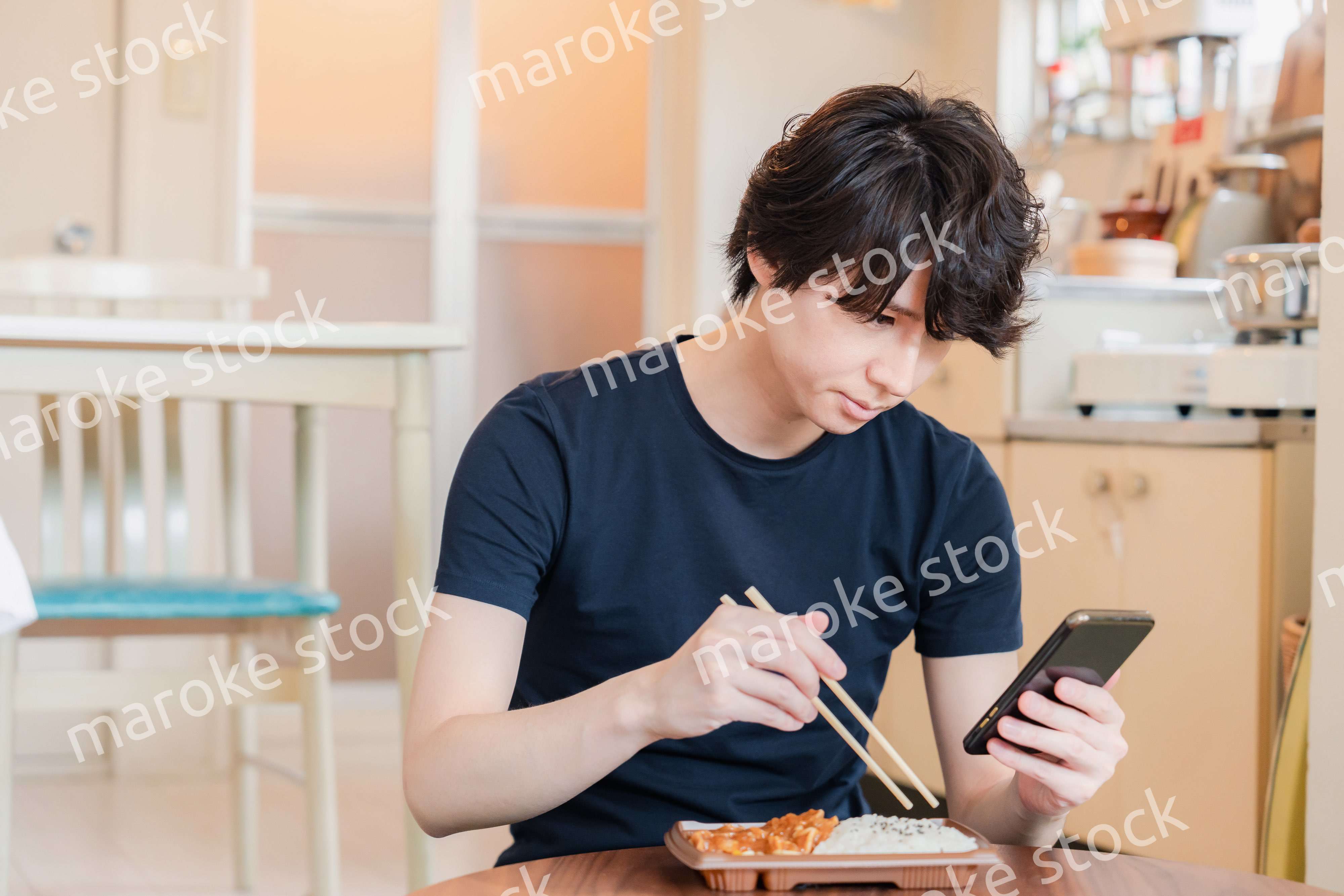 家でコンビニ弁当を食べる若い男性