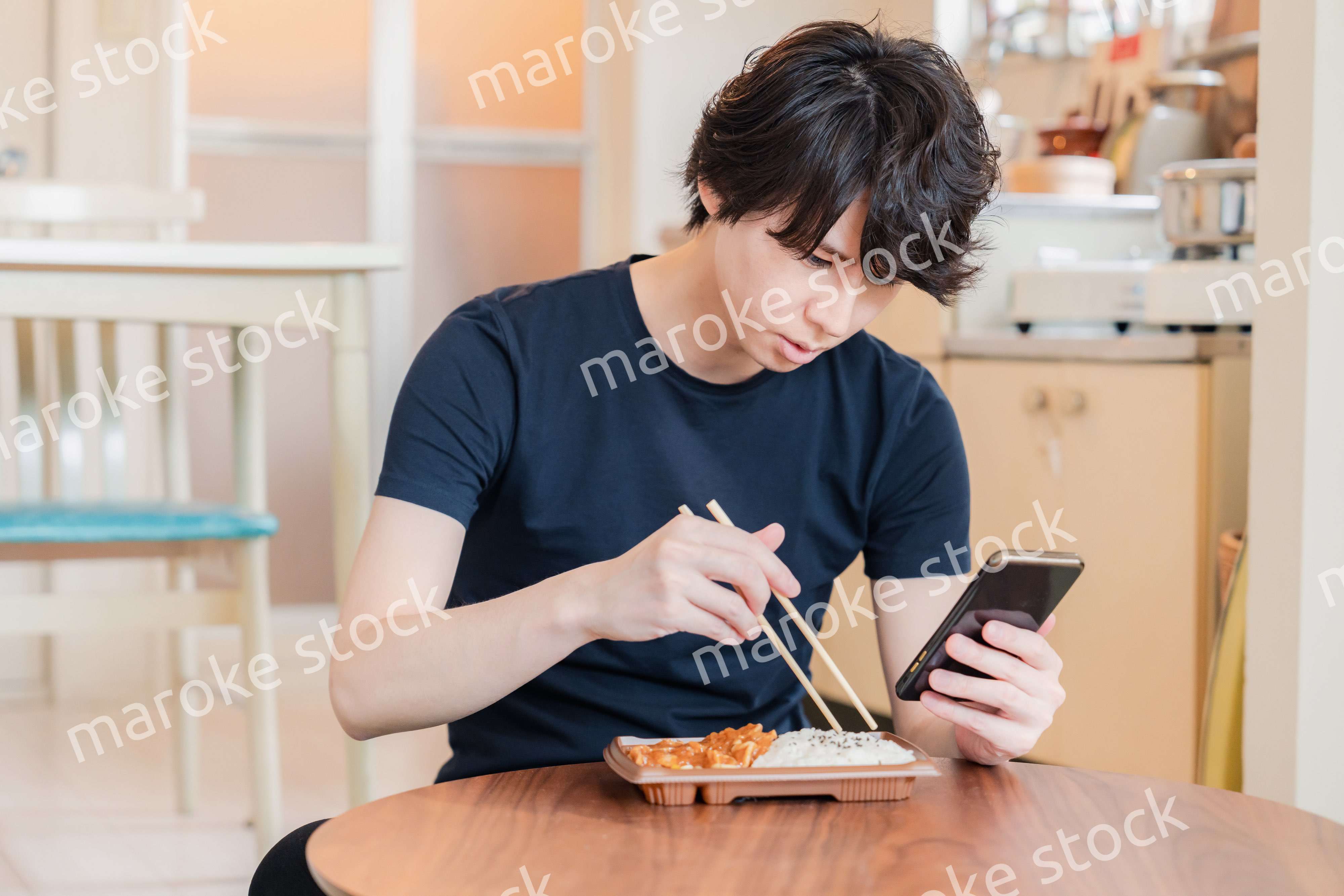 家でコンビニ弁当を食べる若い男性