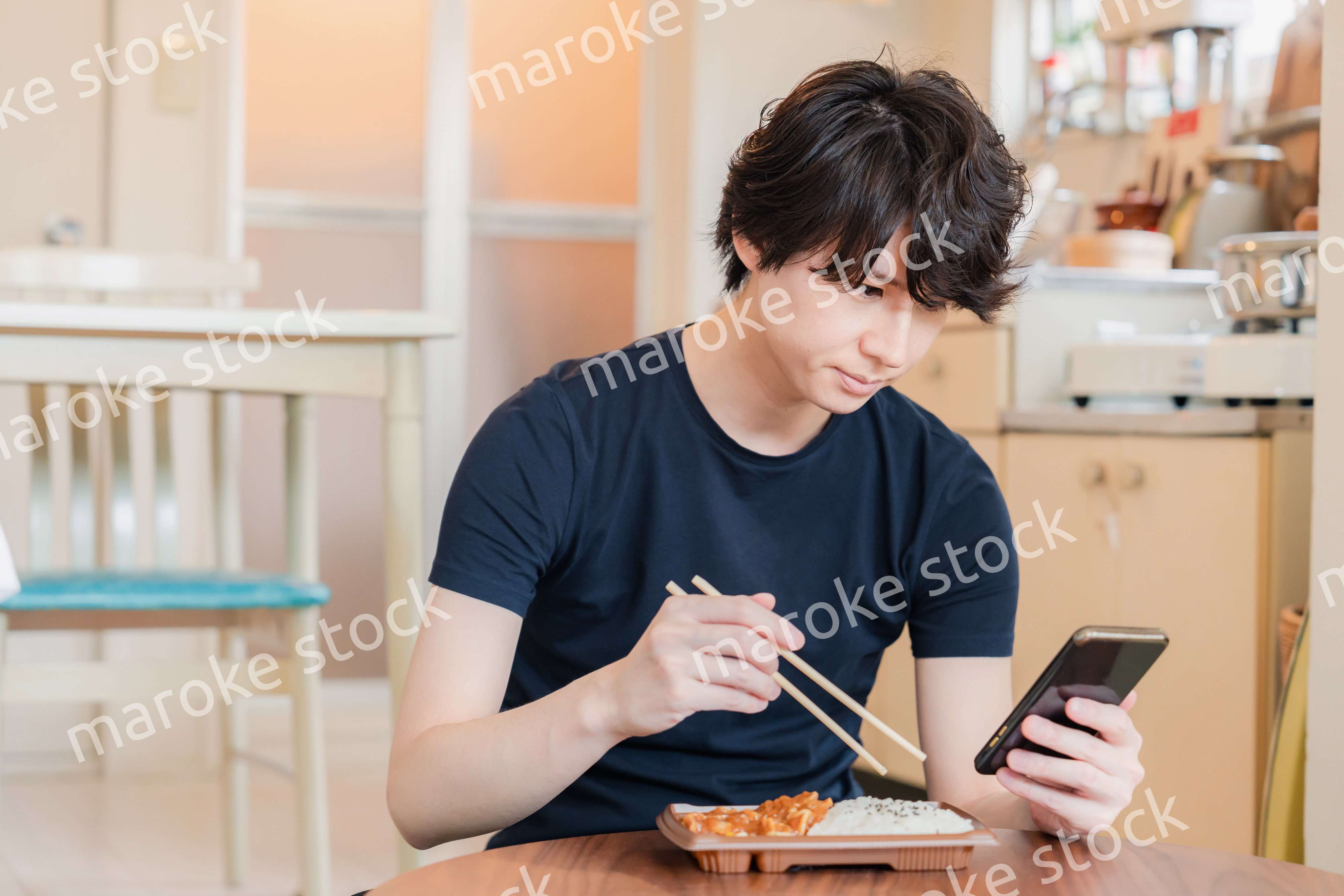 家でコンビニ弁当を食べる若い男性