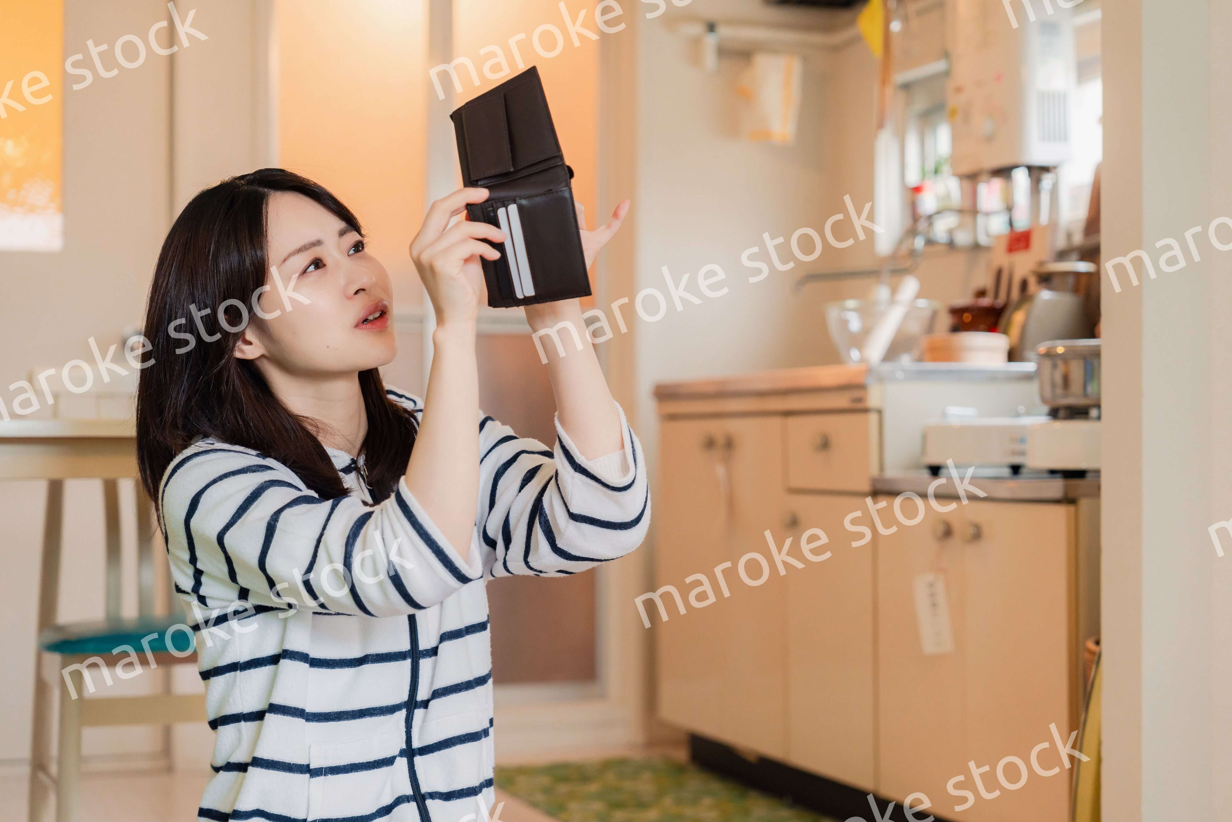 財布の中を確認して落ち込む若い女性