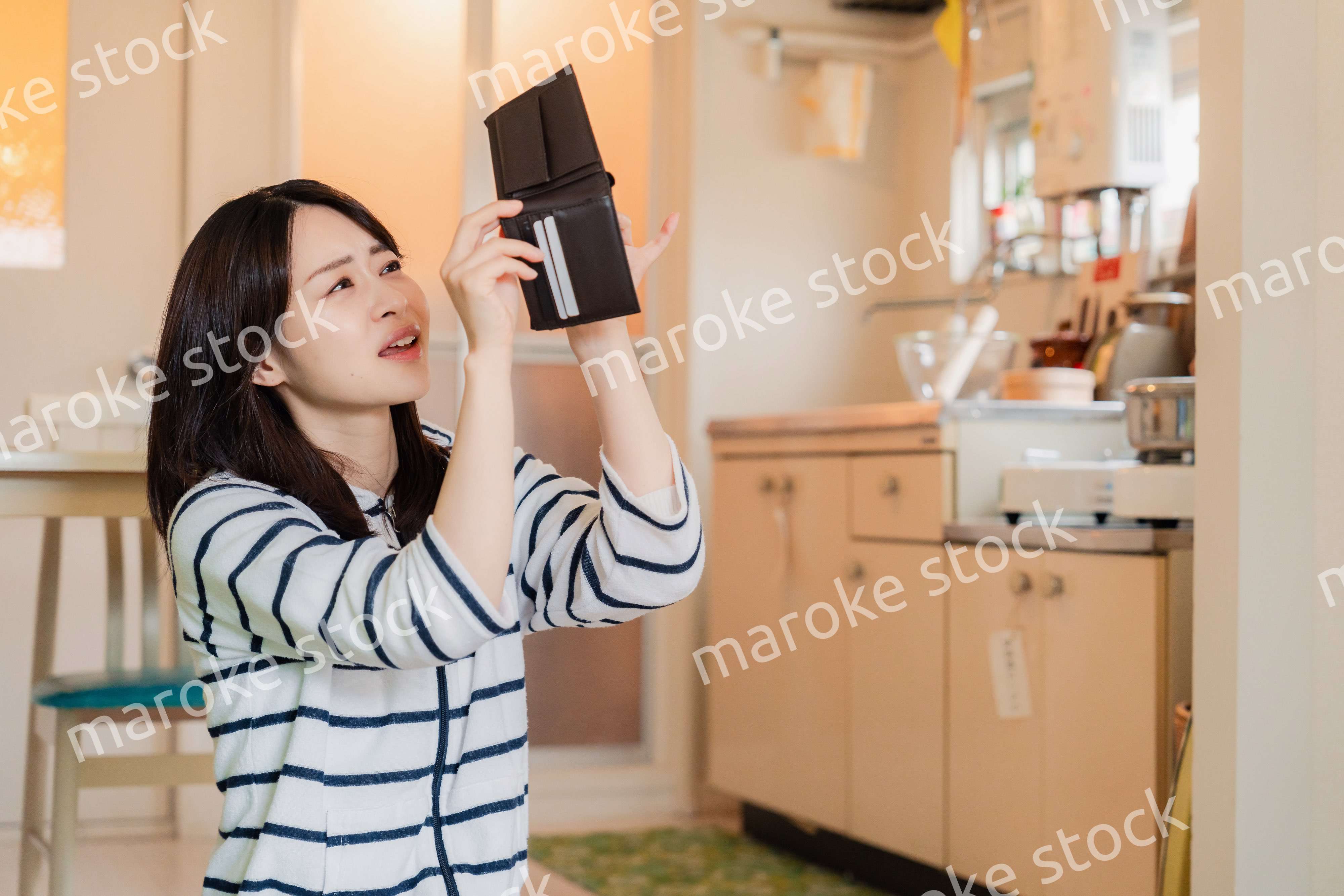 財布の中を確認して落ち込む若い女性