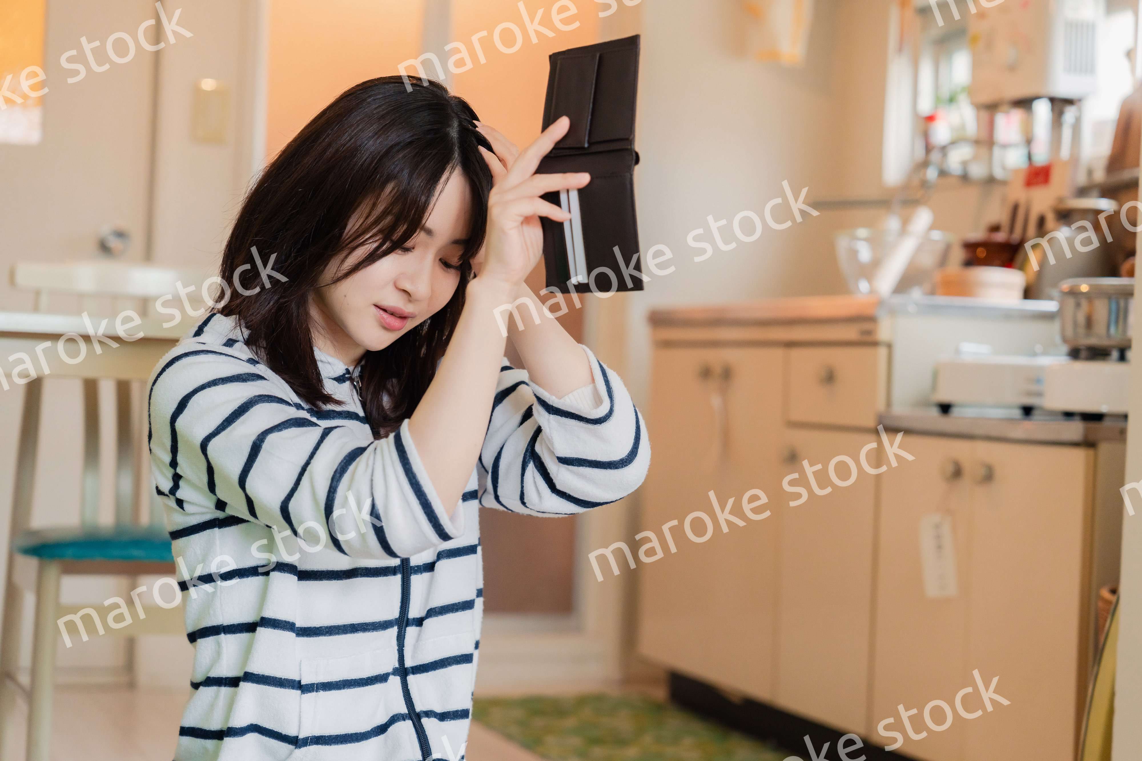 財布の中を確認して落ち込む若い女性