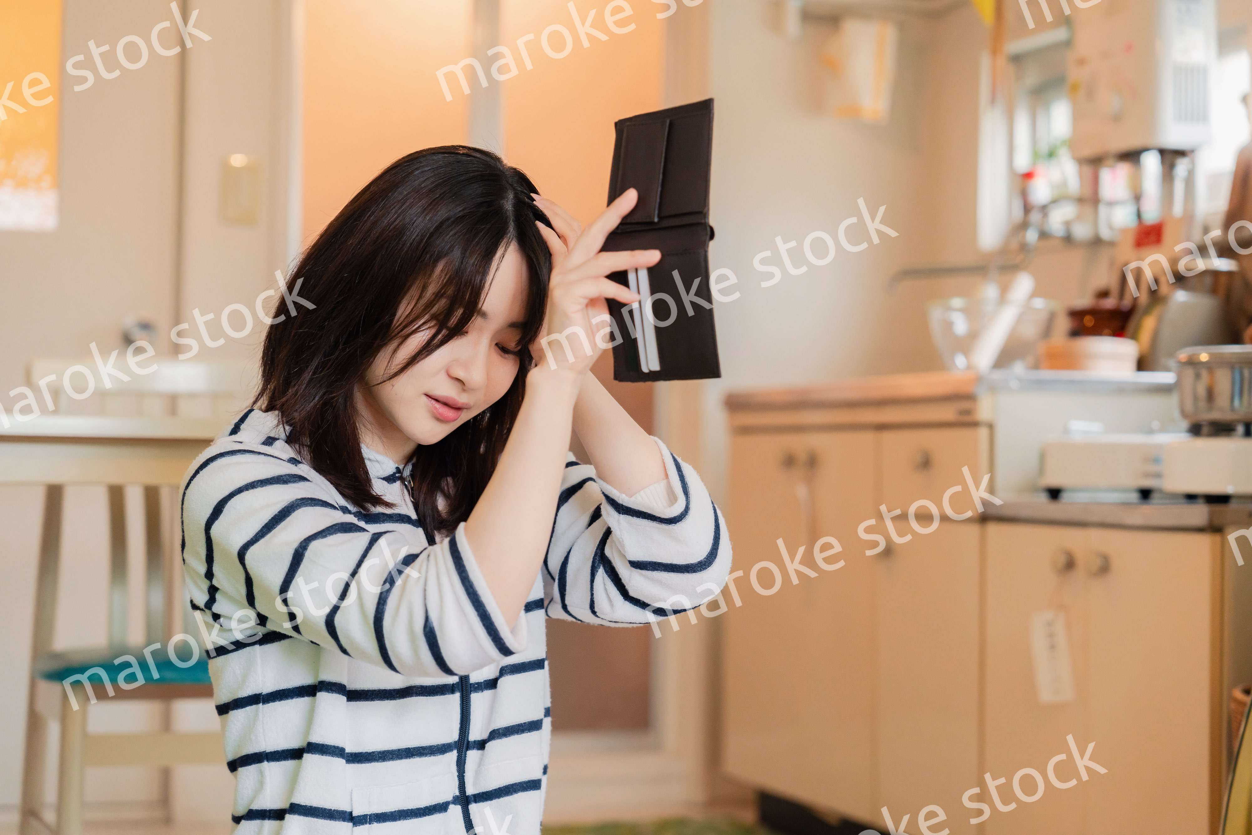財布の中を確認して落ち込む若い女性