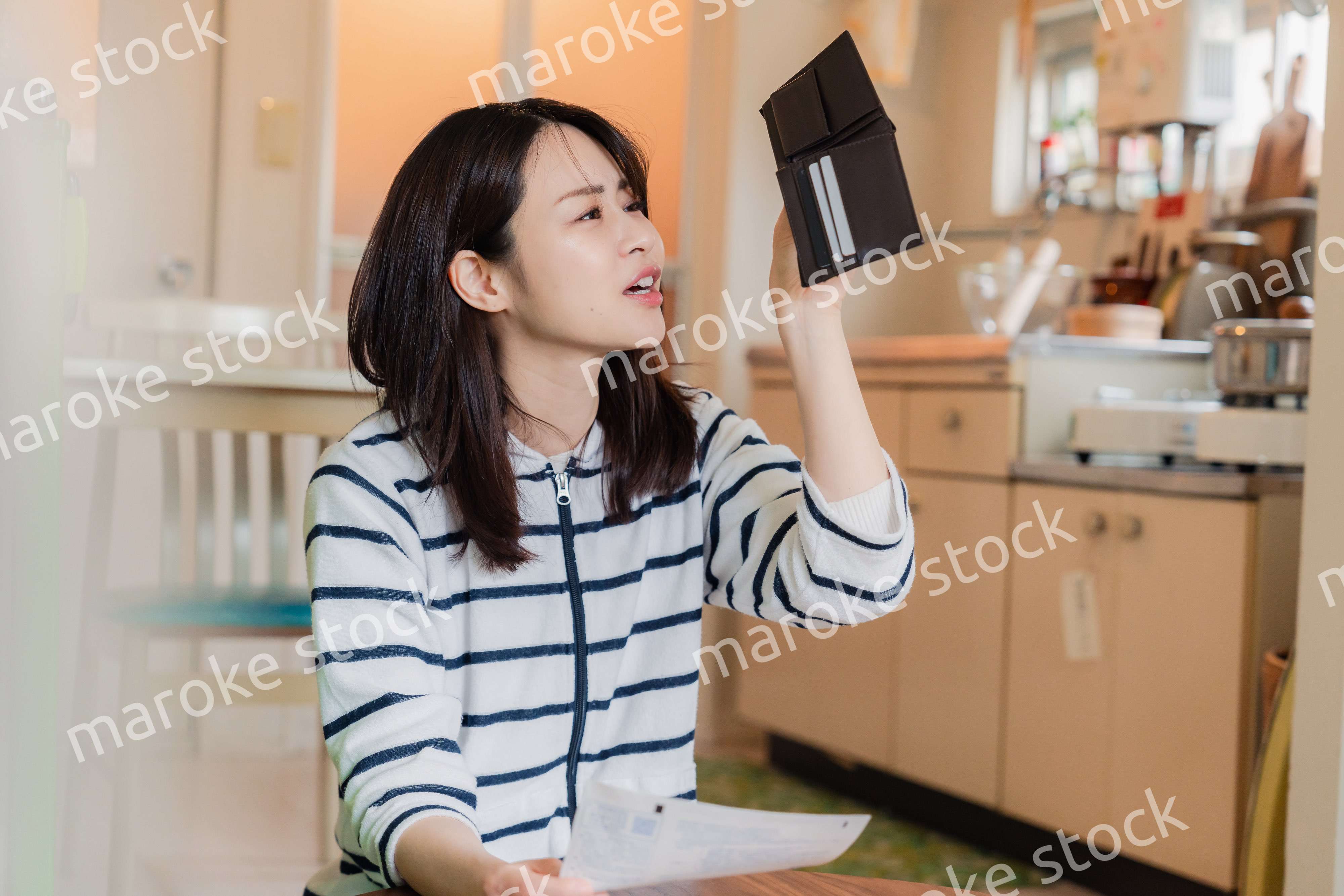 財布の中を確認して落ち込む若い女性