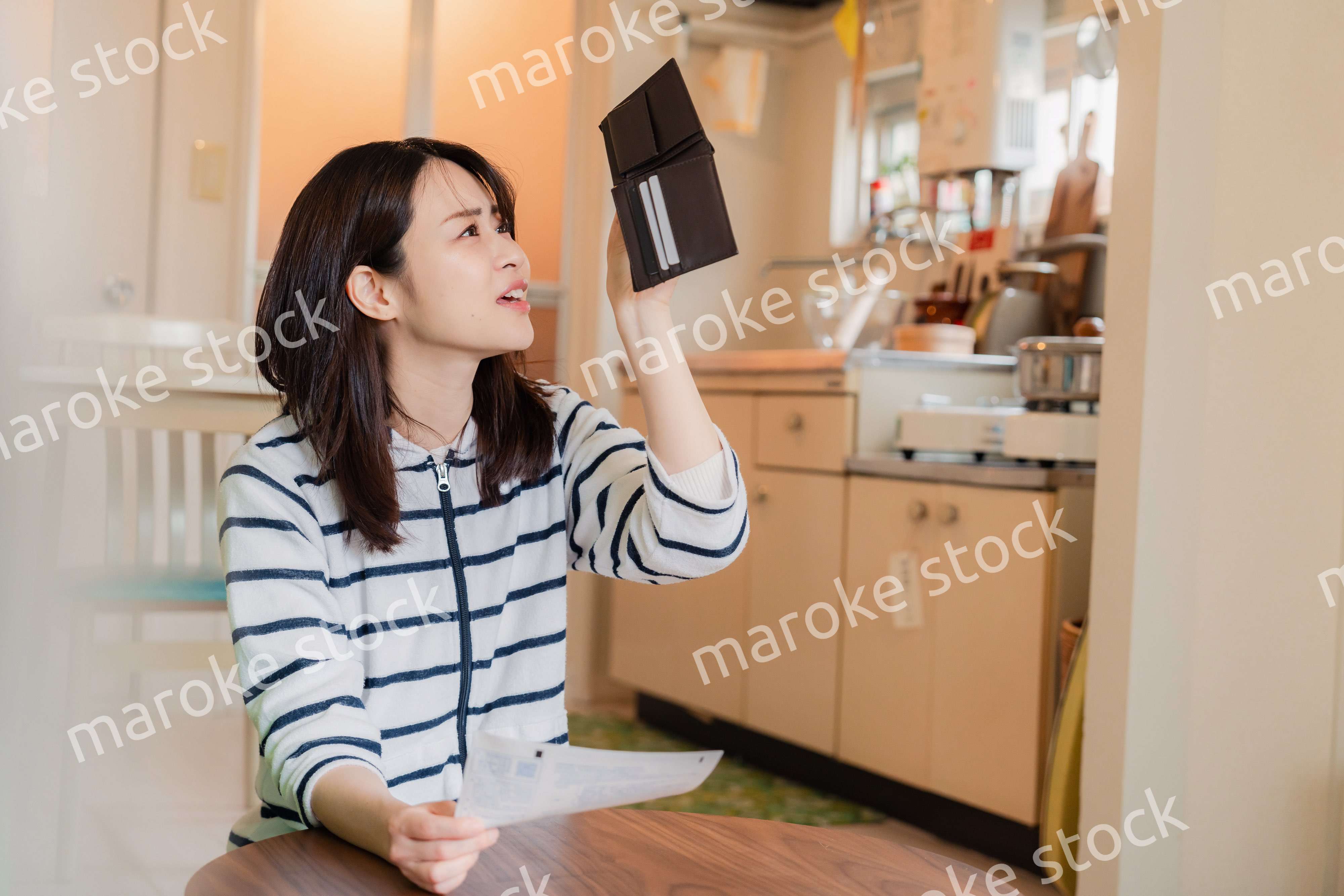 財布の中を確認して落ち込む若い女性