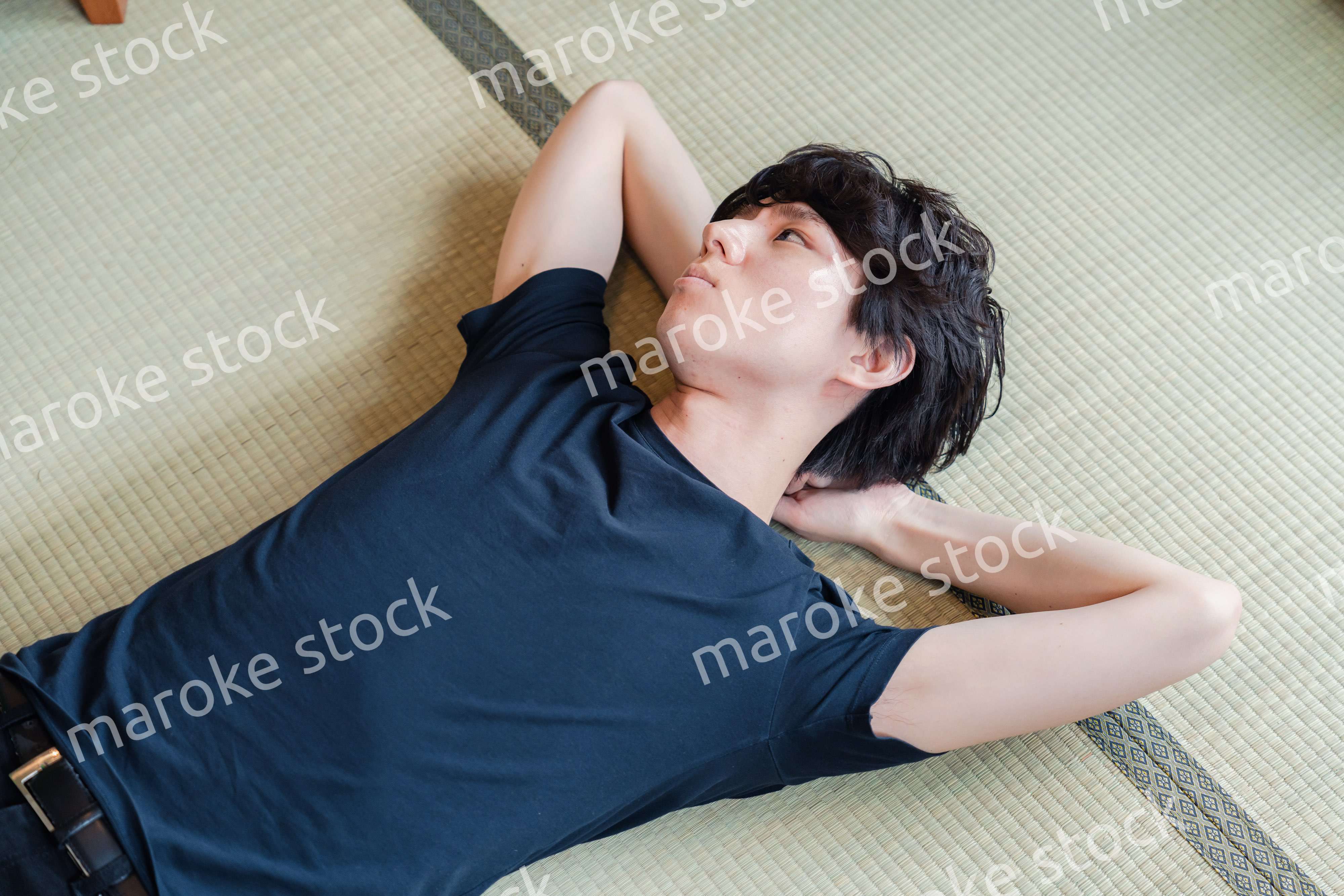 畳の上で寝転がる若い男性