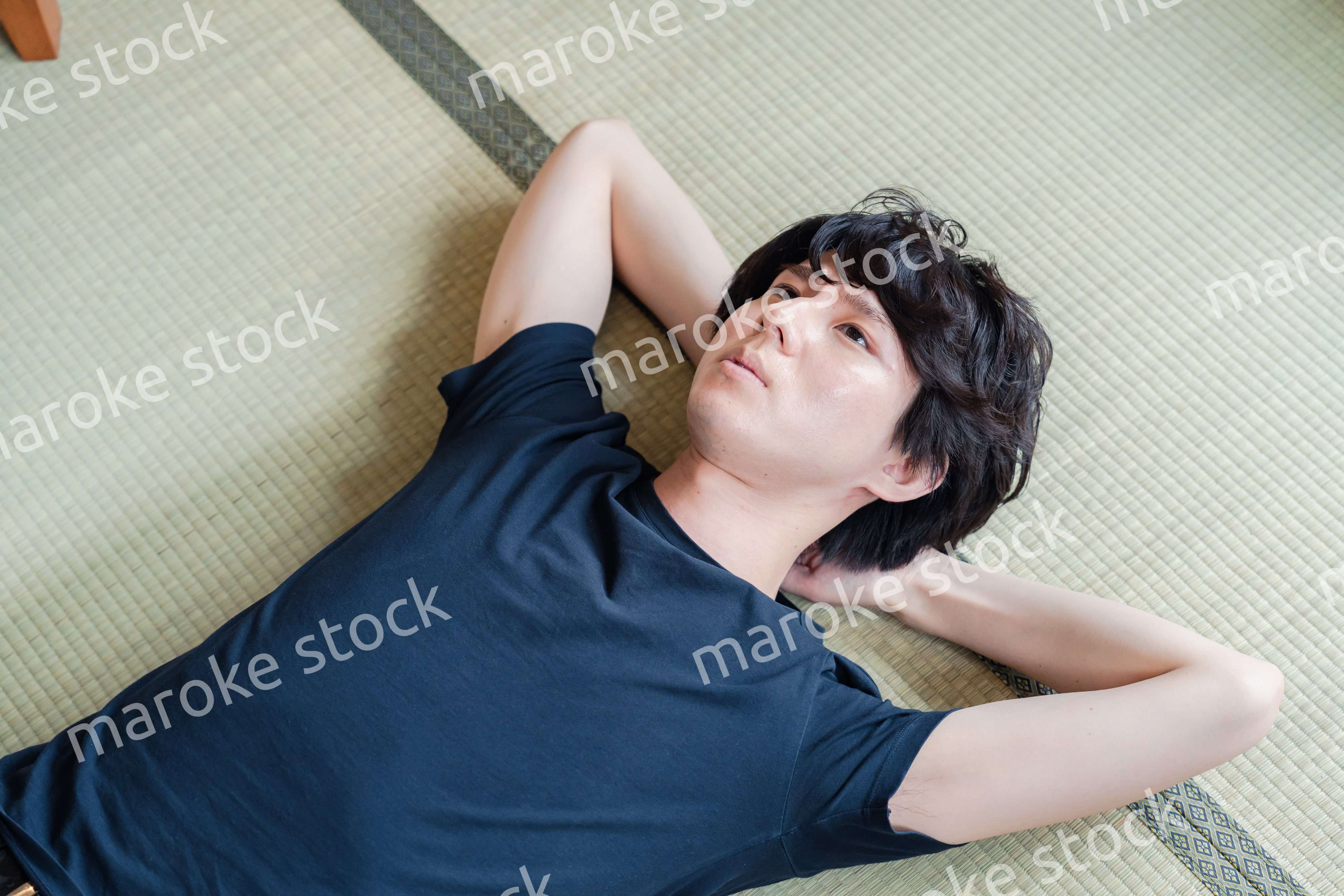 畳の上で寝転がる若い男性