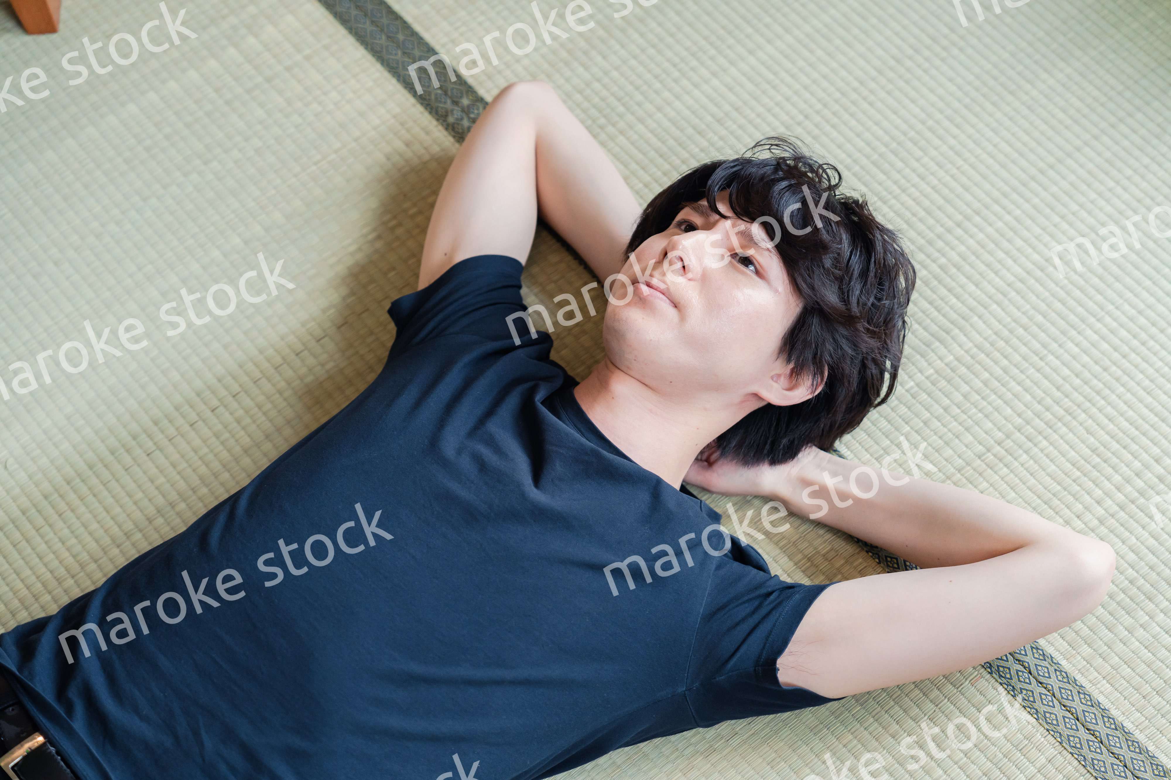 畳の上で寝転がる若い男性
