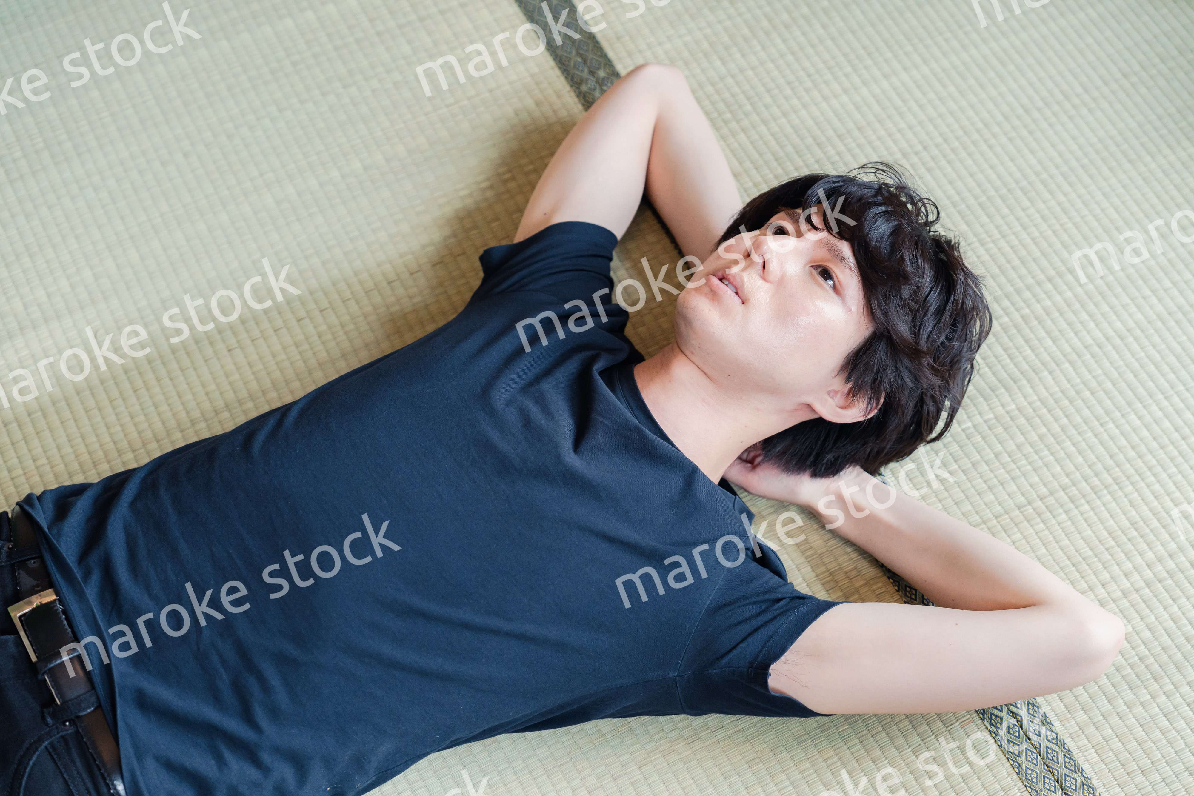 畳の上で寝転がる若い男性