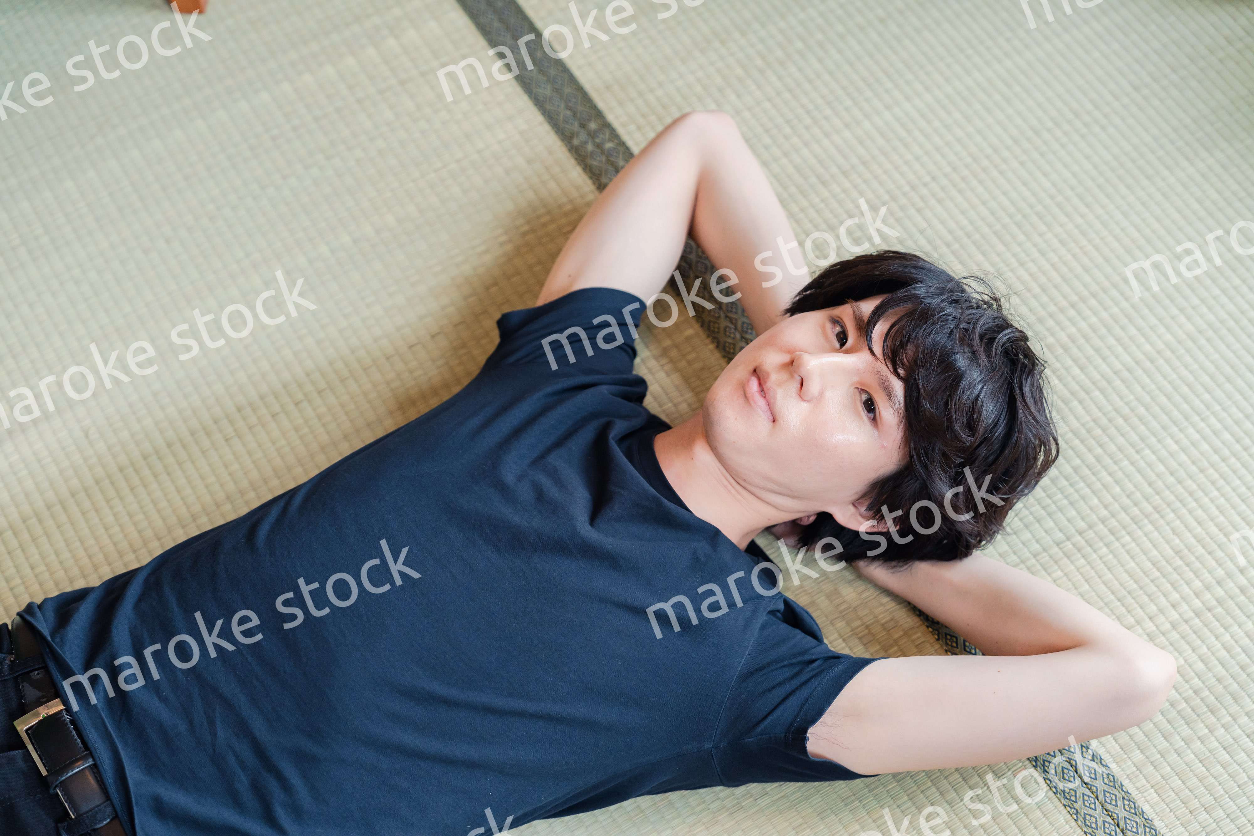 畳の上で寝転がる若い男性