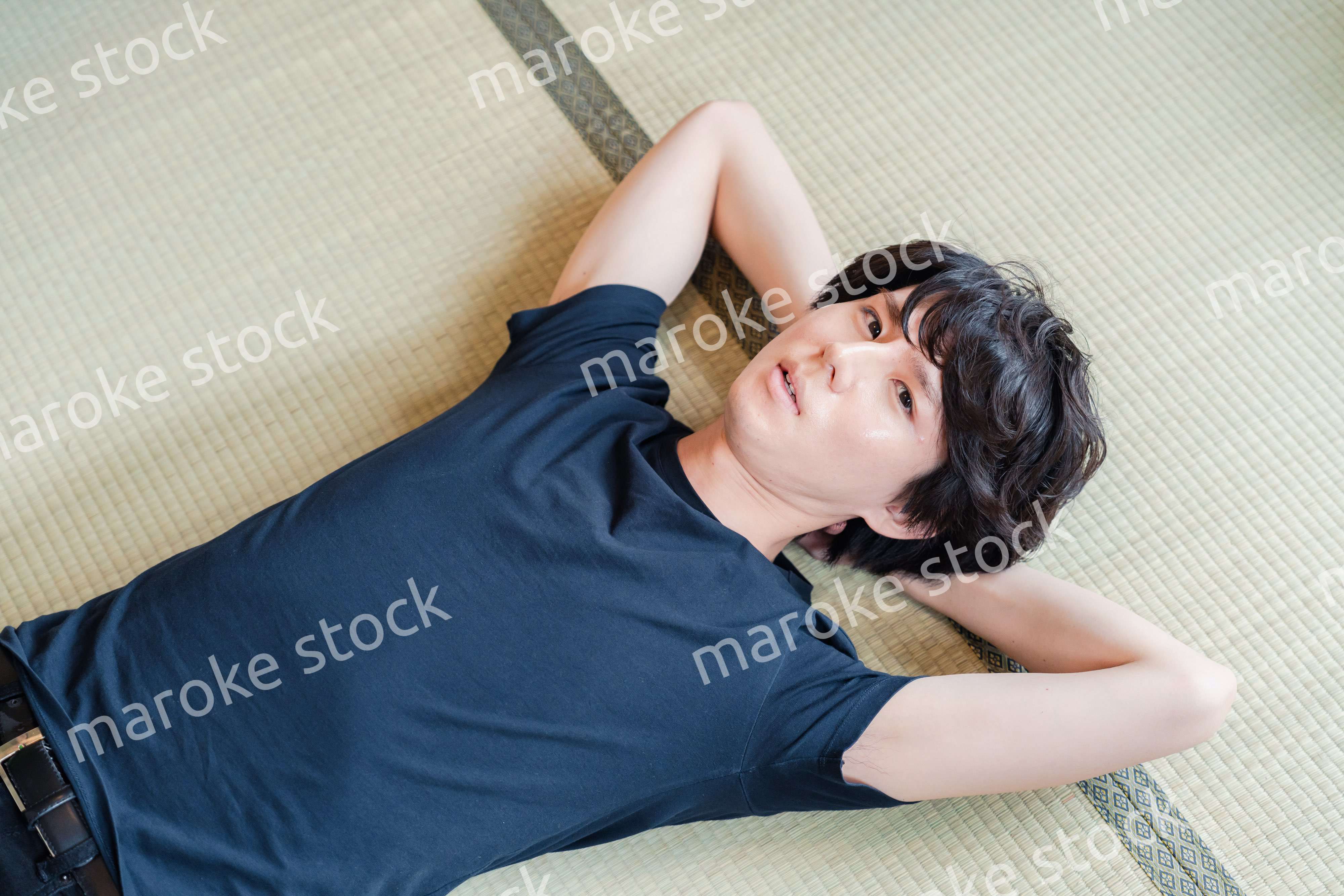 畳の上で寝転がる若い男性