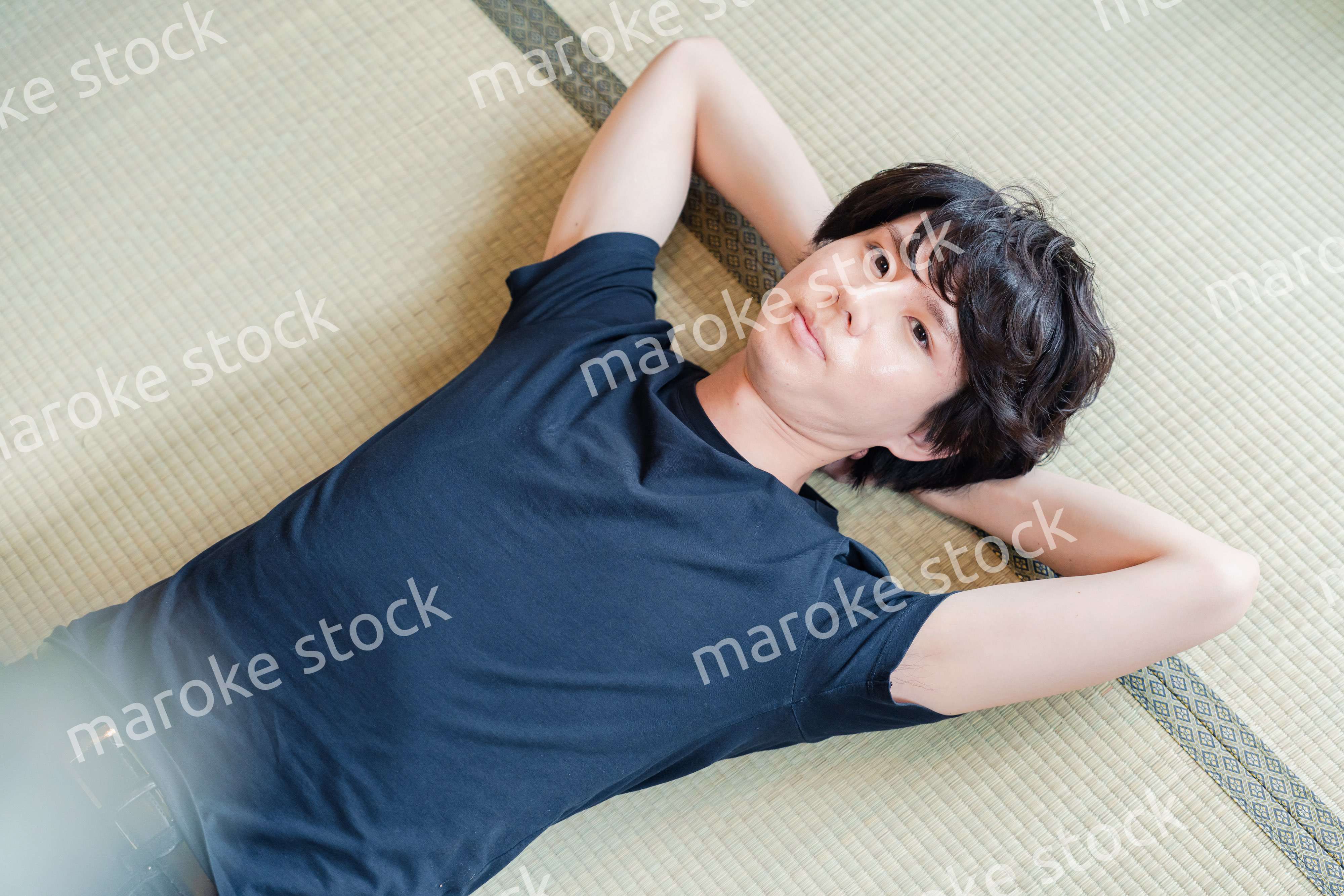 畳の上で寝転がる若い男性