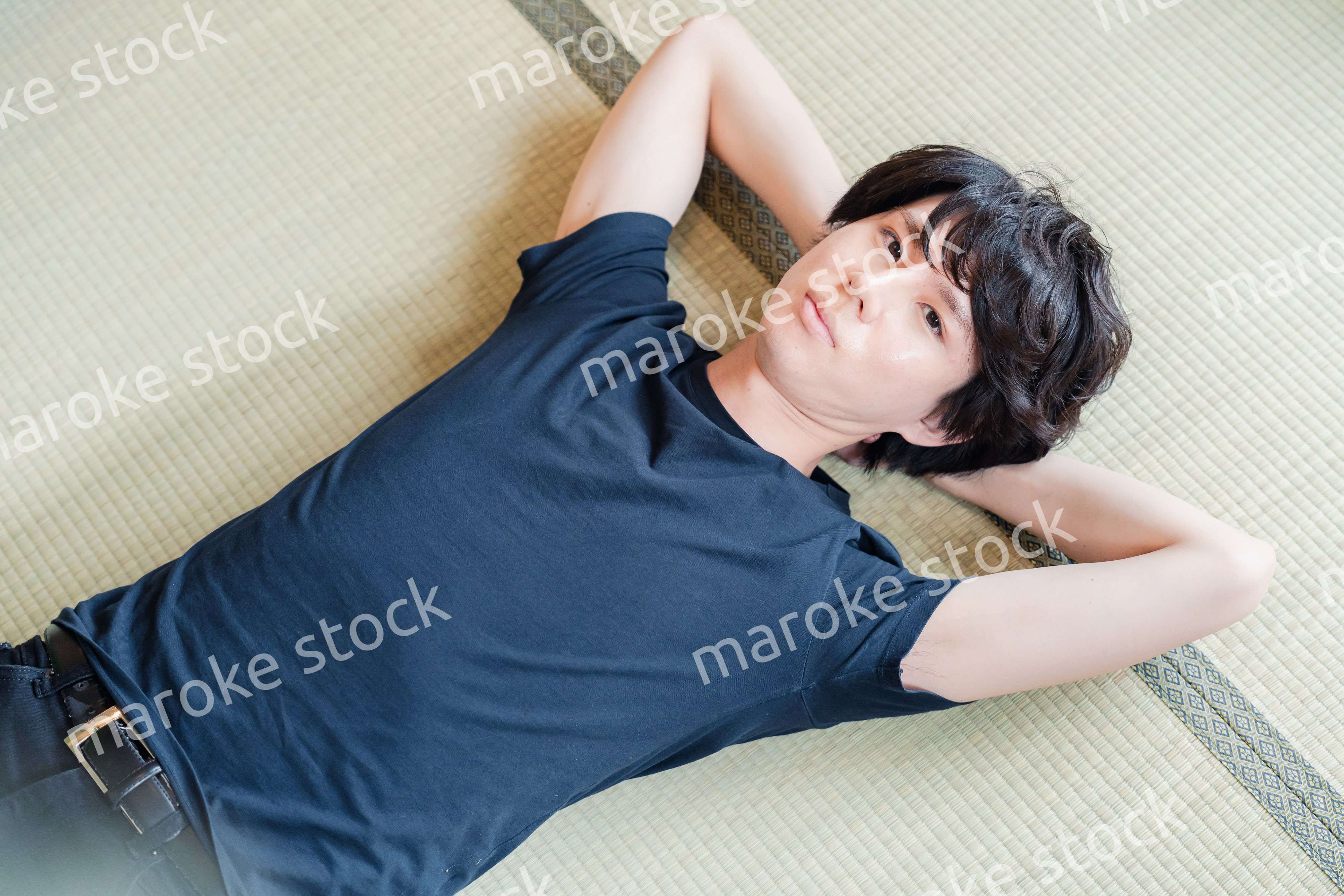 畳の上で寝転がる若い男性