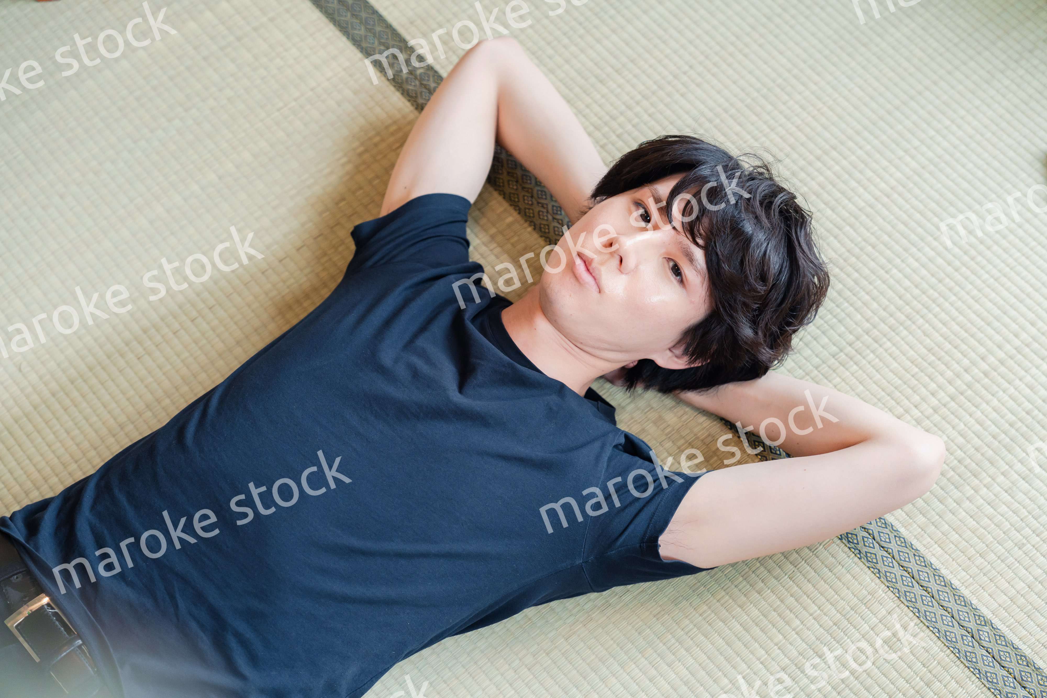 畳の上で寝転がる若い男性