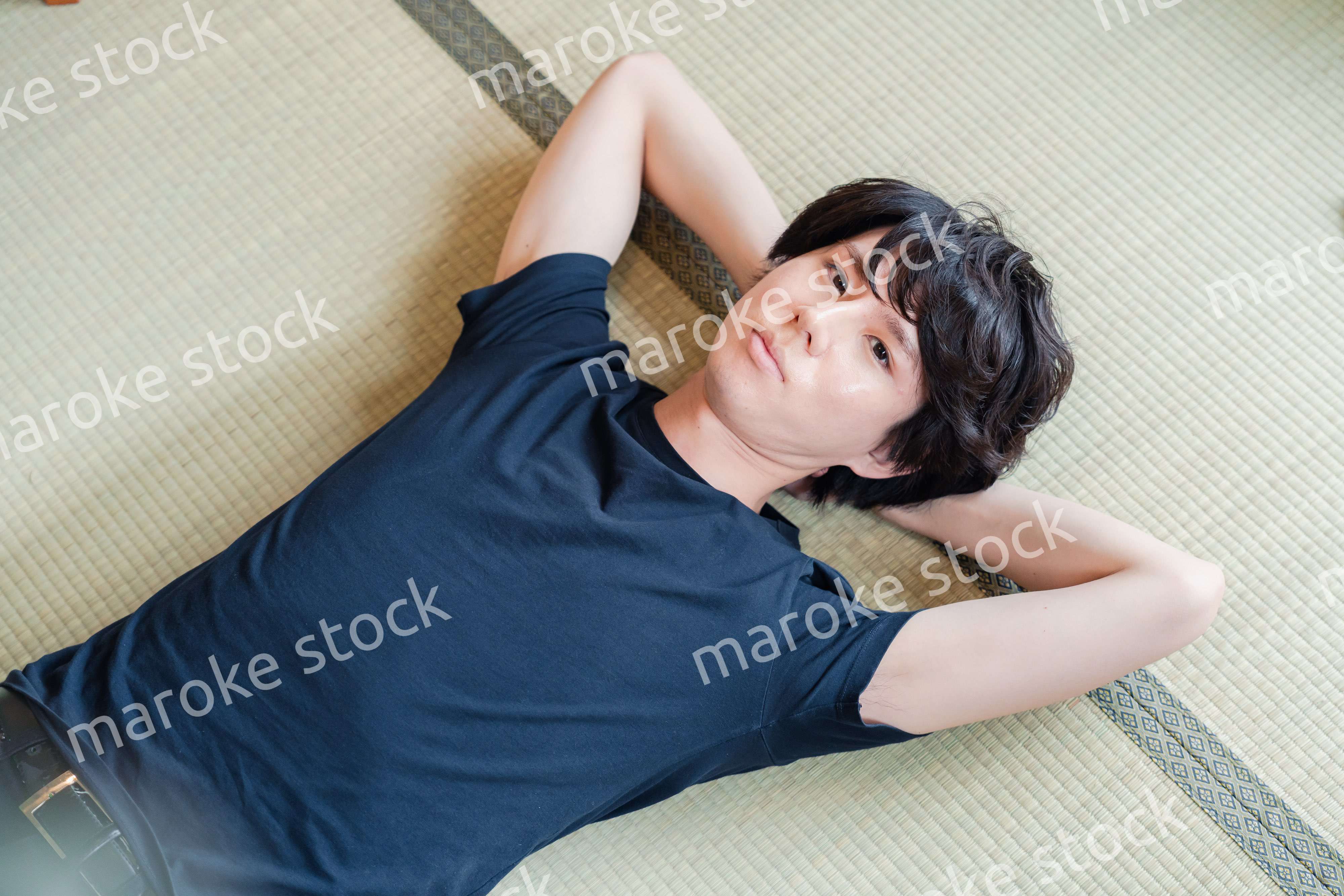 畳の上で寝転がる若い男性