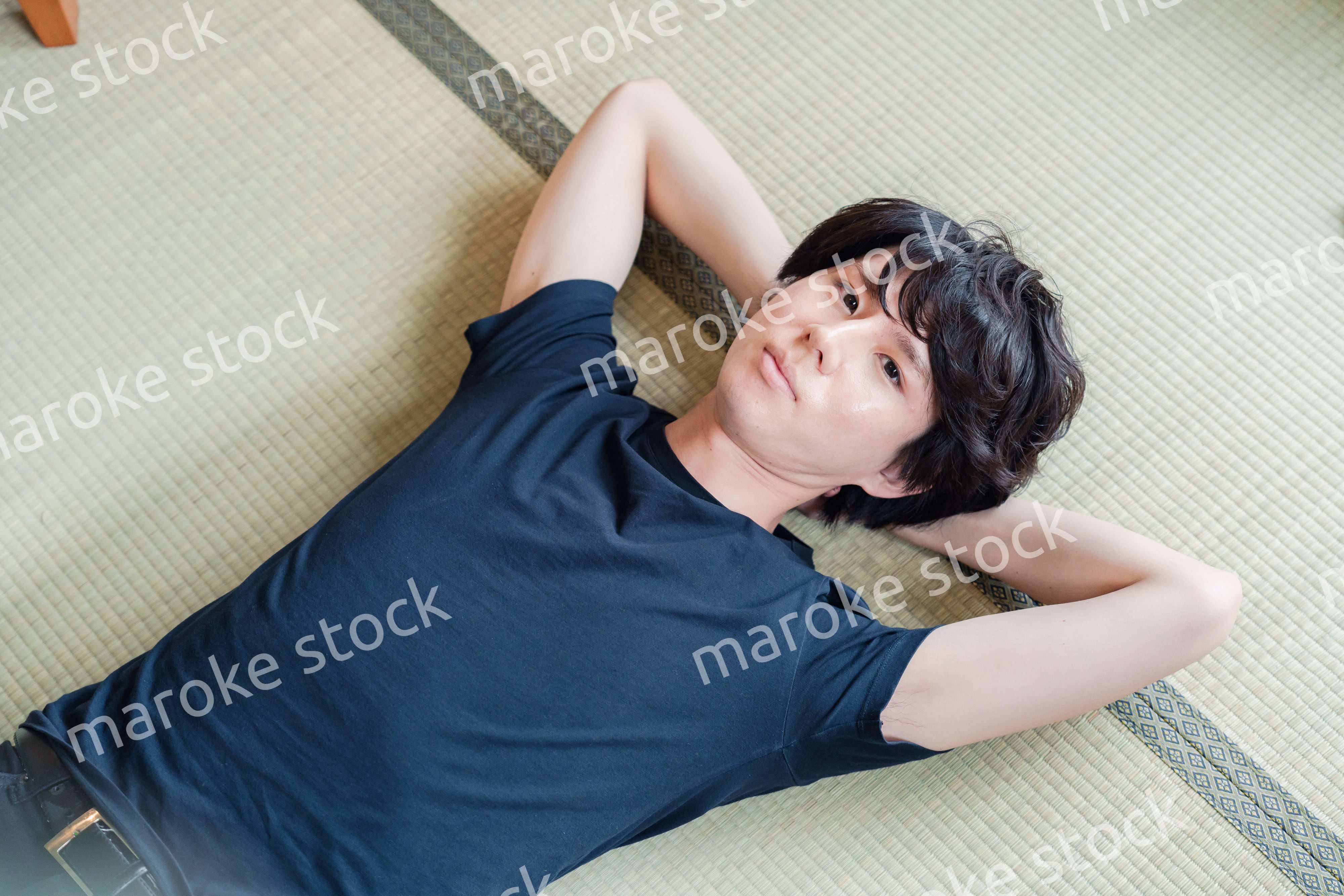 畳の上で寝転がる若い男性