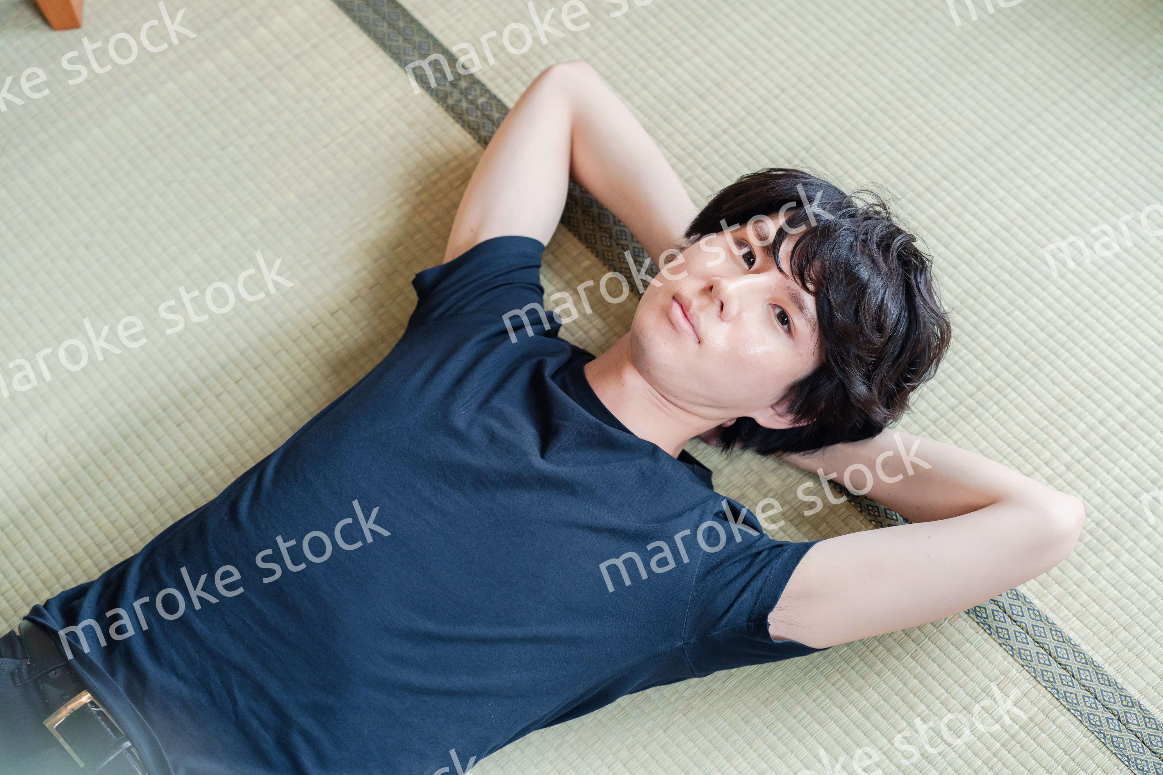 畳の上で寝転がる若い男性