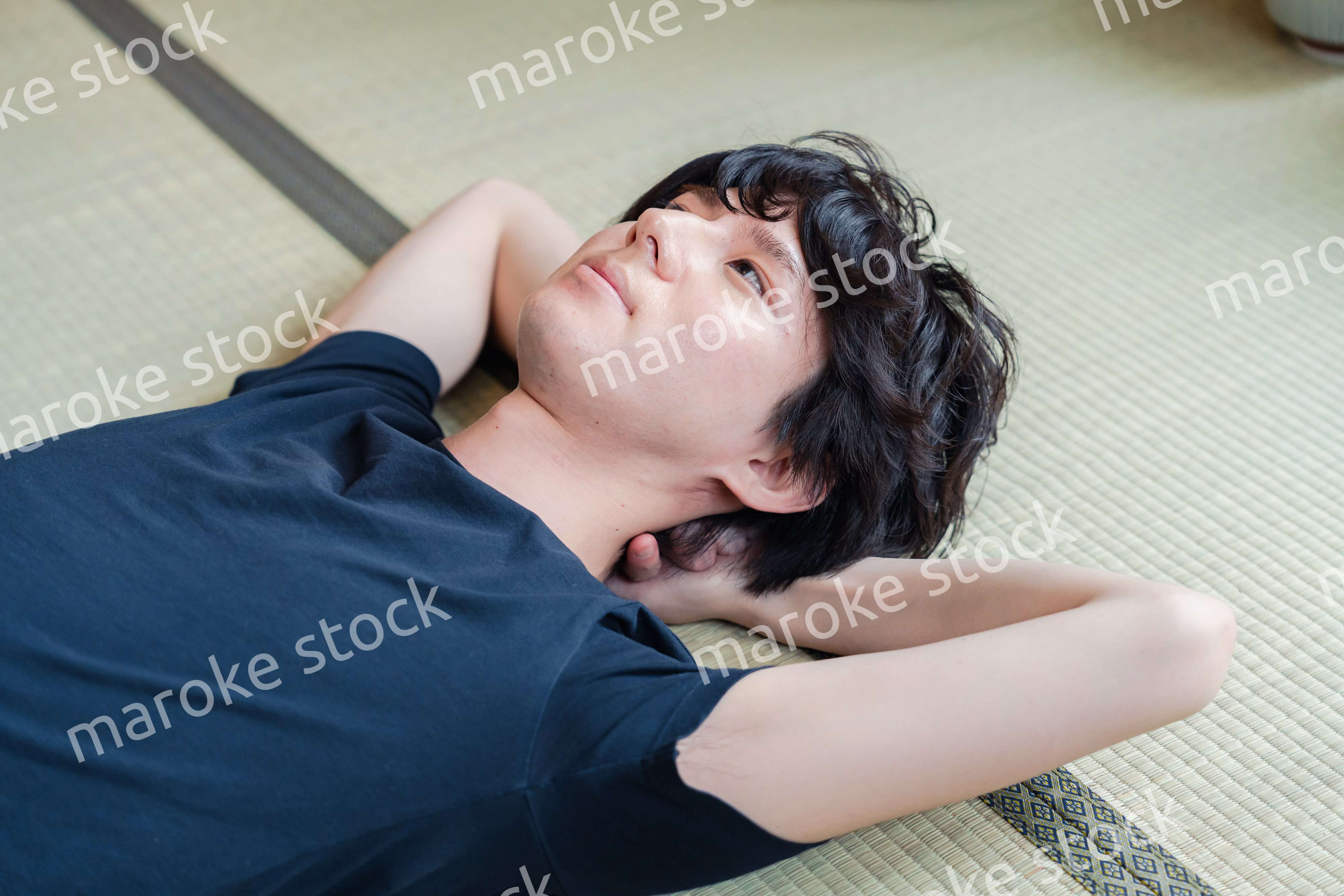 畳の上で寝転がる若い男性