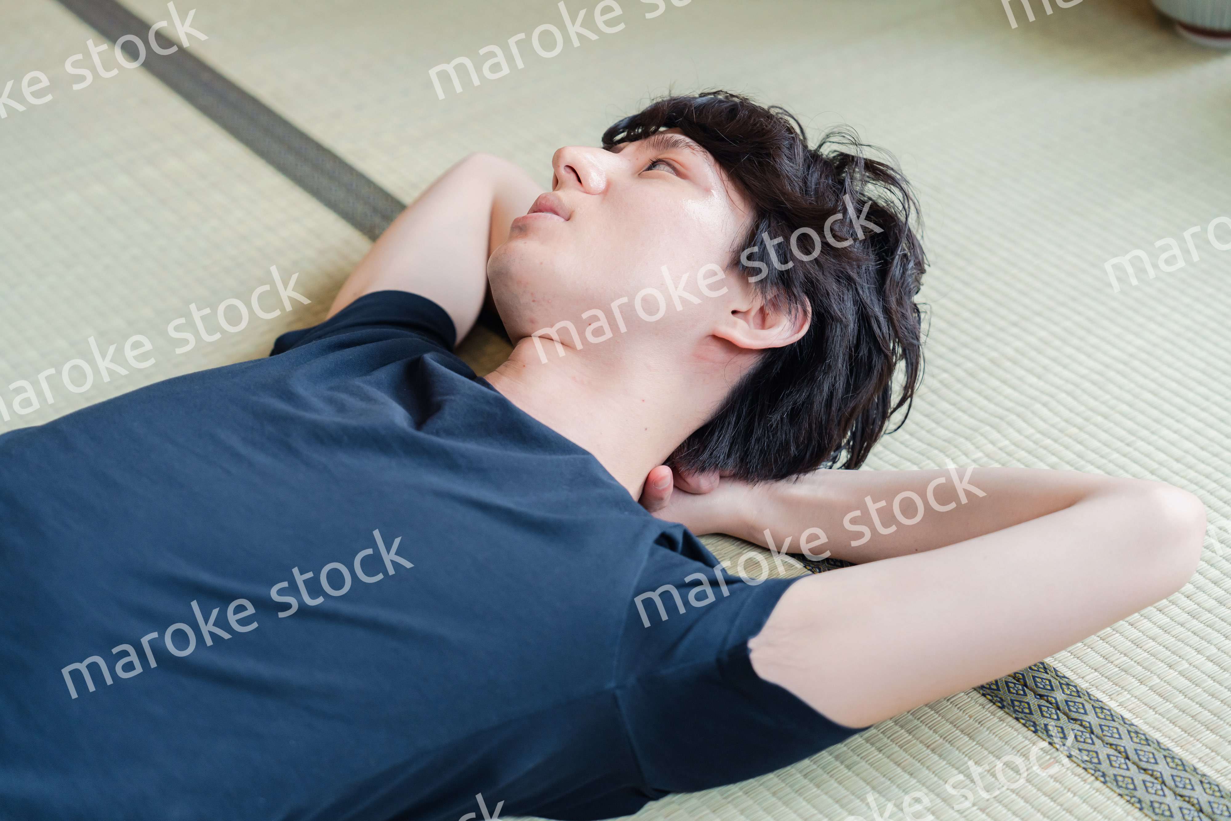 畳の上で寝転がる若い男性