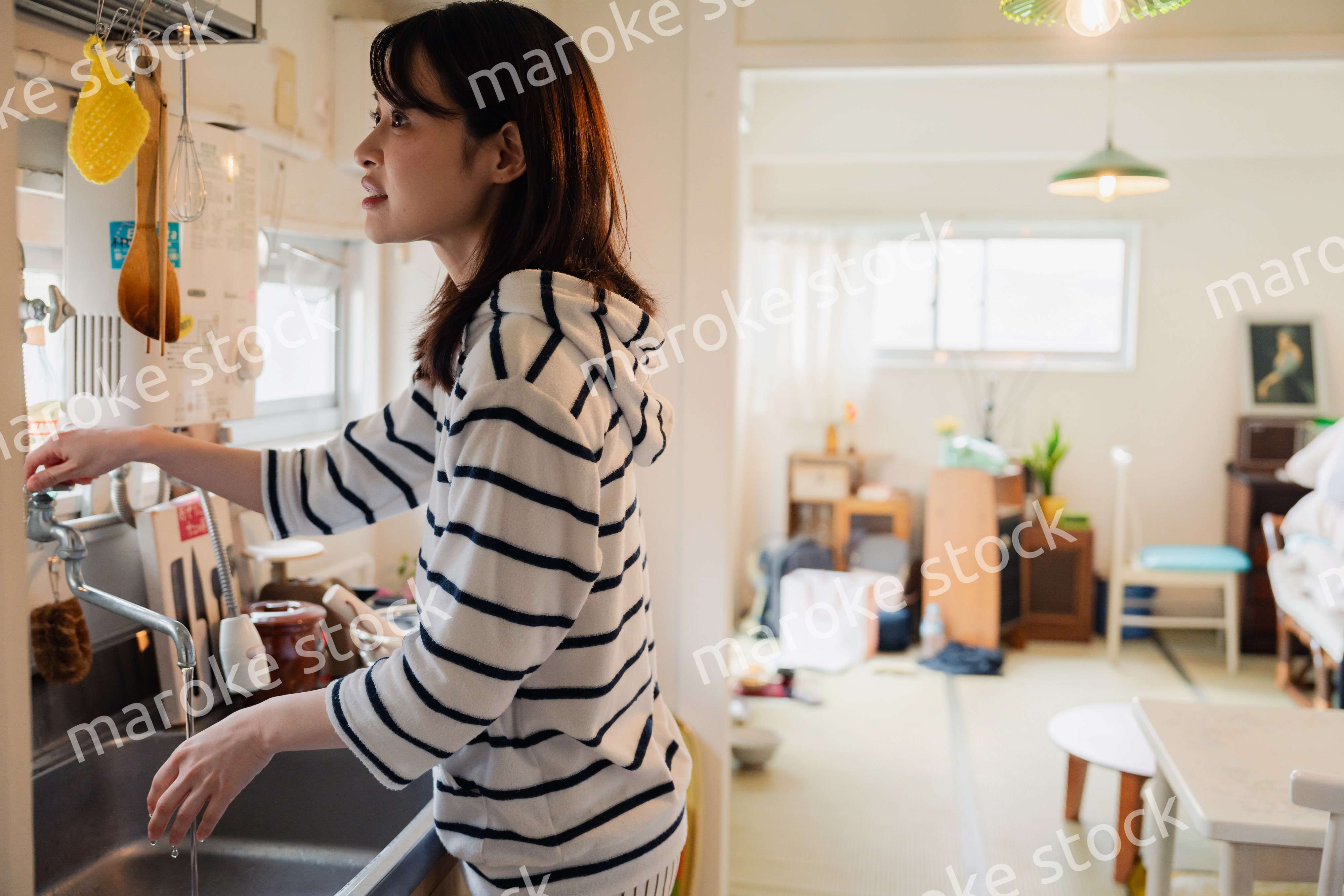 団地の台所で家事をする女性