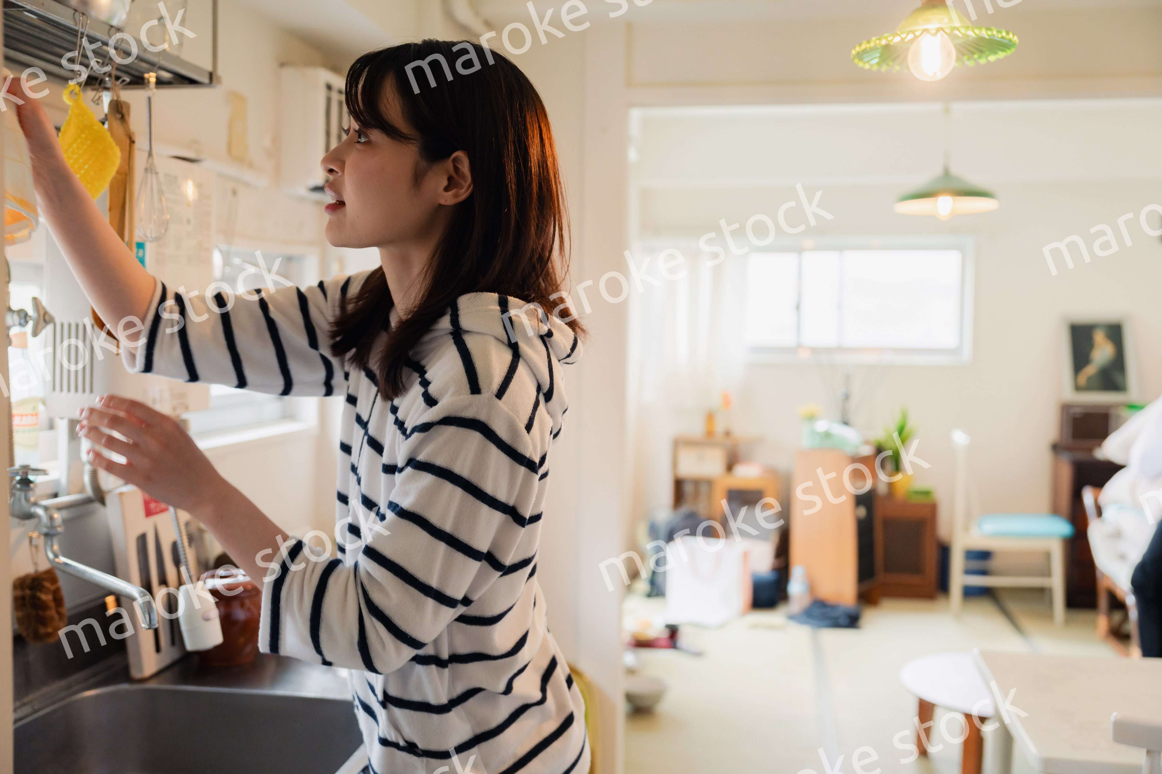 団地の台所で家事をする女性