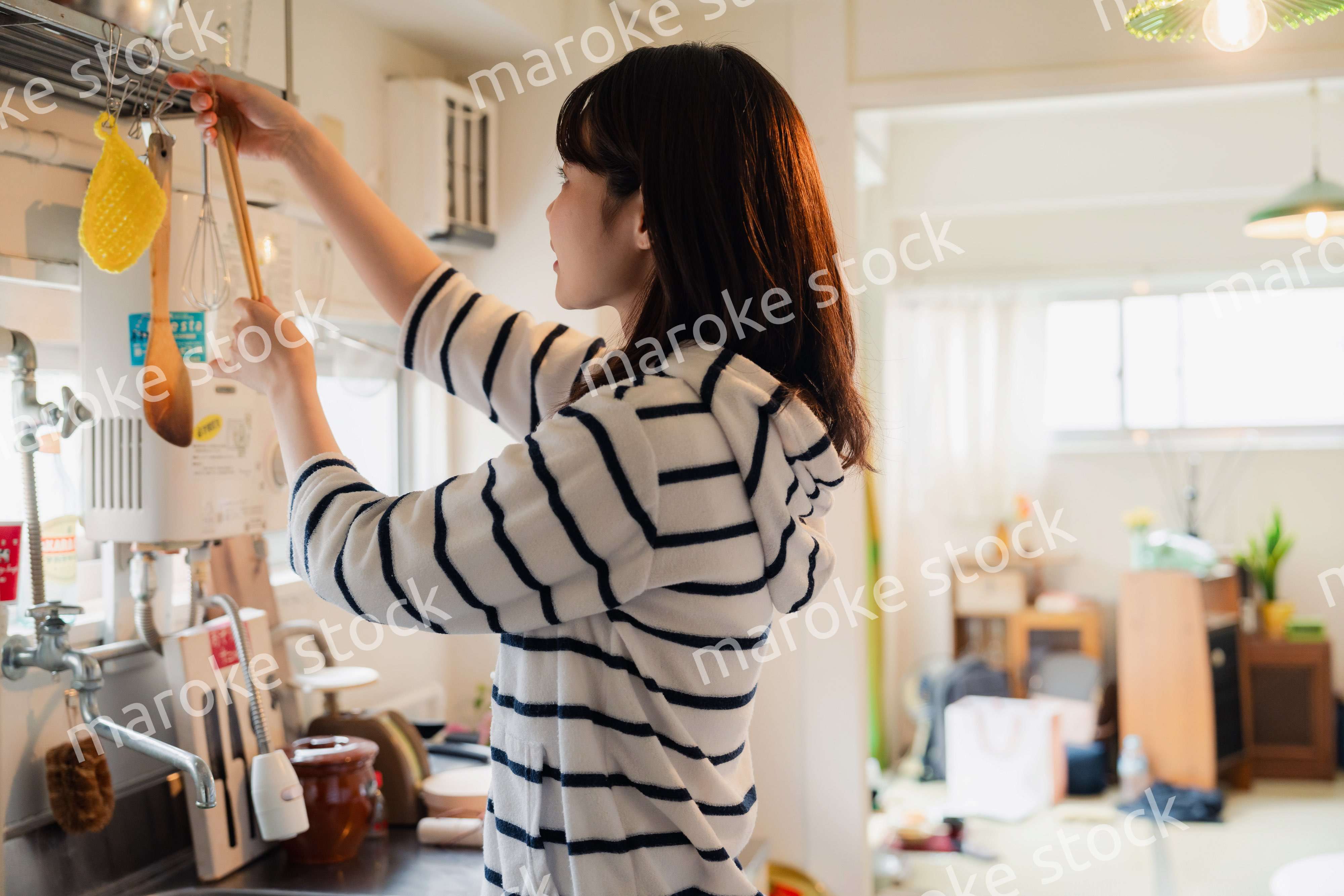団地の台所で家事をする女性