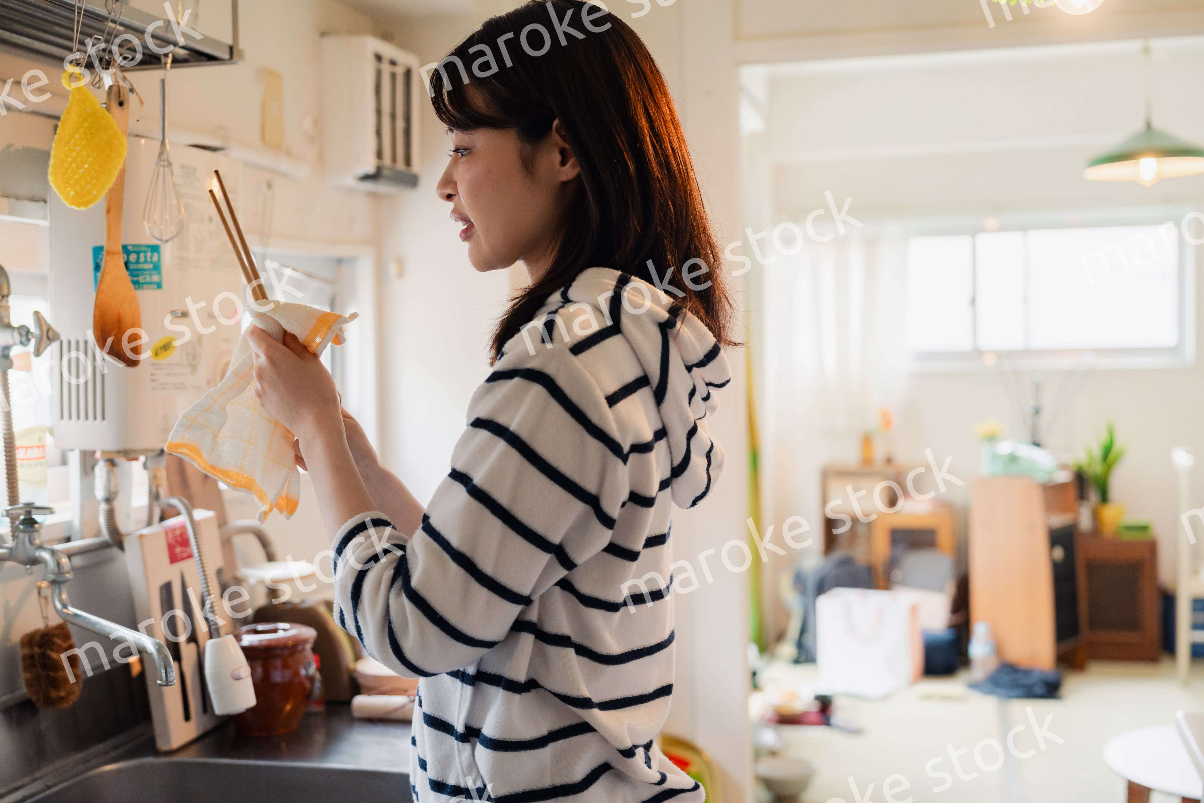 団地の台所で家事をする女性