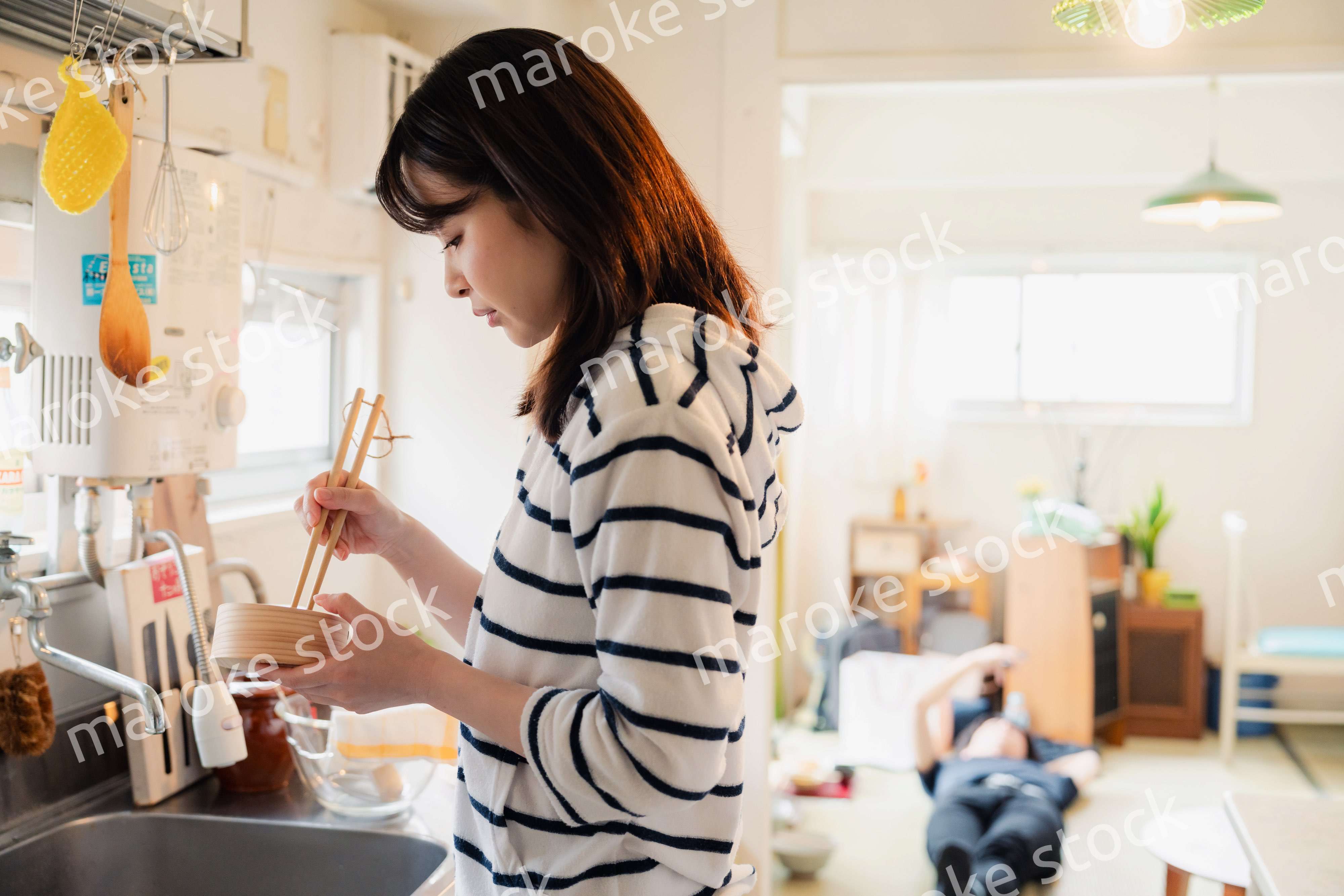 妻がお弁当を作っている後ろで寝転ぶ夫