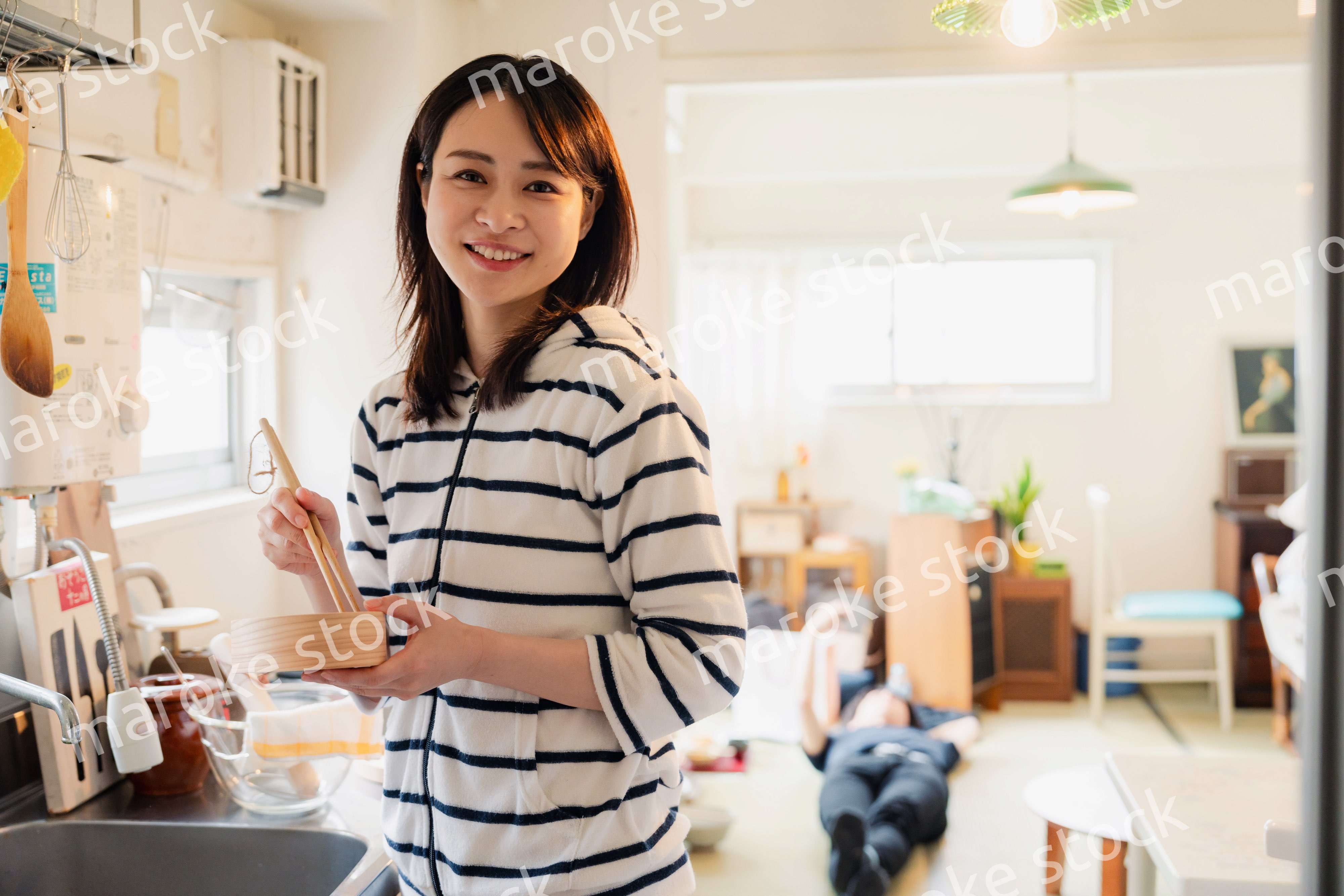 妻がお弁当を作っている後ろで寝転ぶ夫