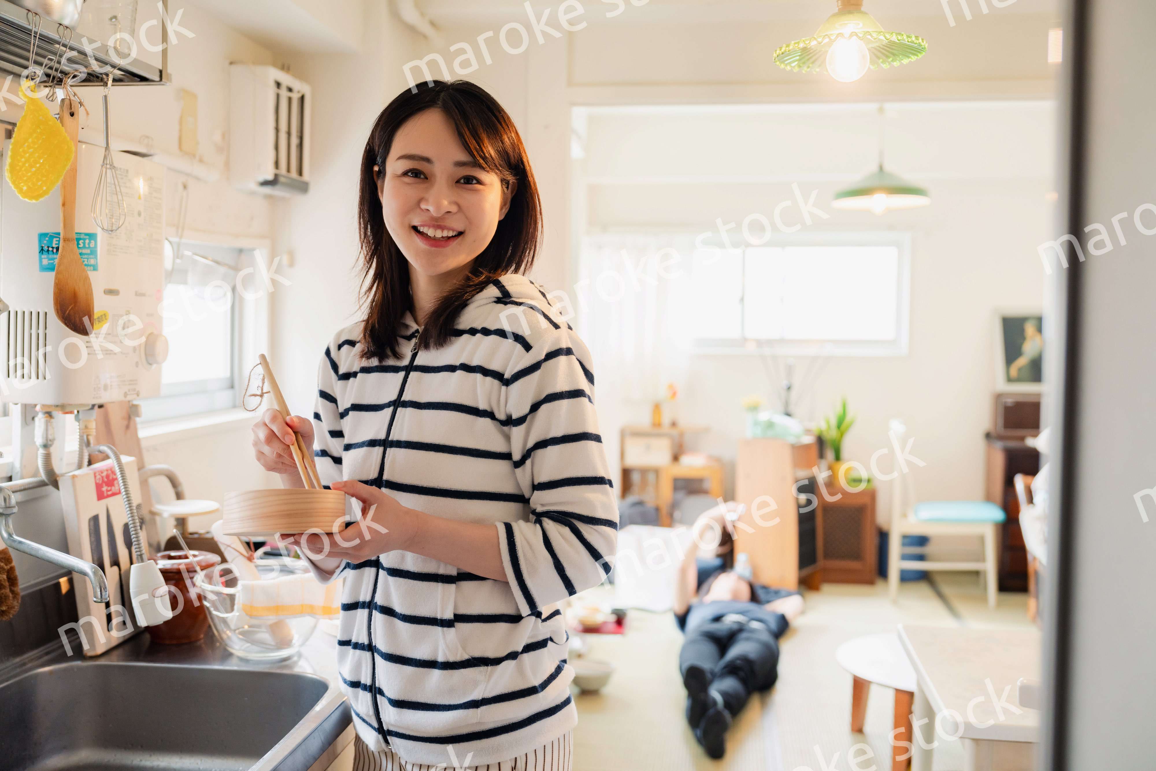 妻がお弁当を作っている後ろで寝転ぶ夫