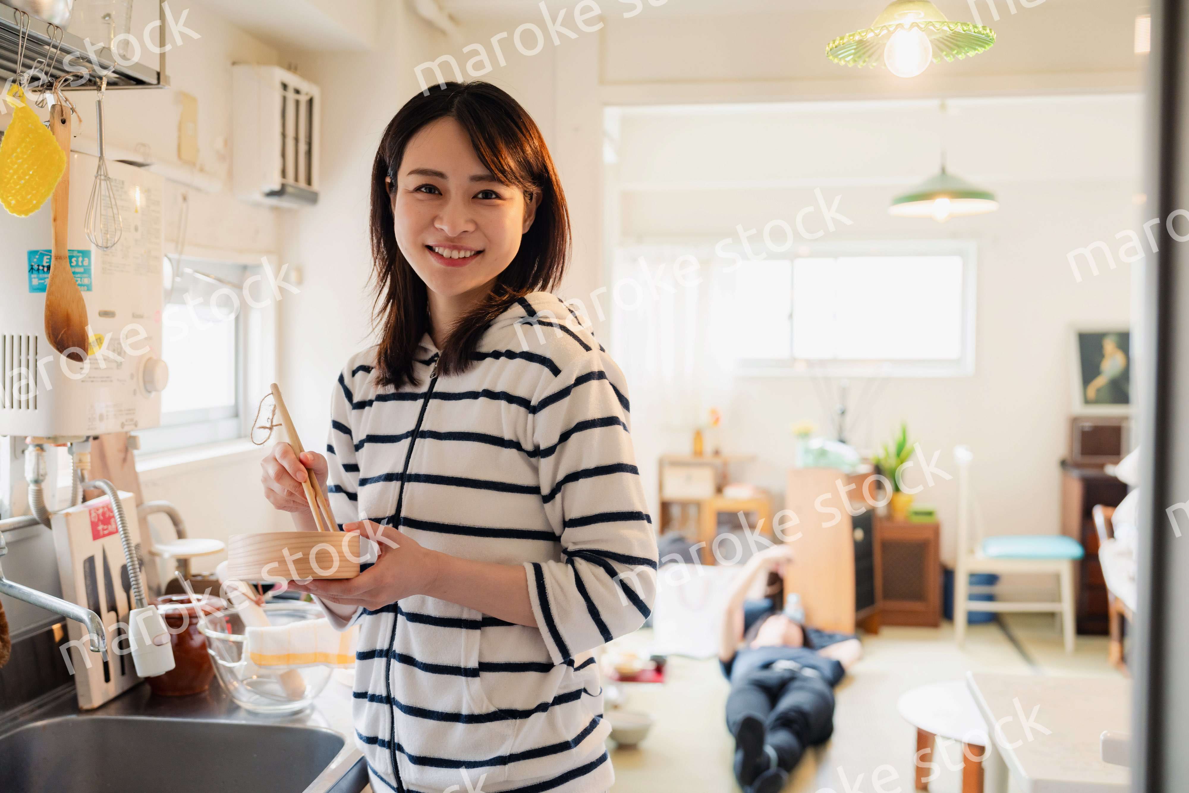 妻がお弁当を作っている後ろで寝転ぶ夫