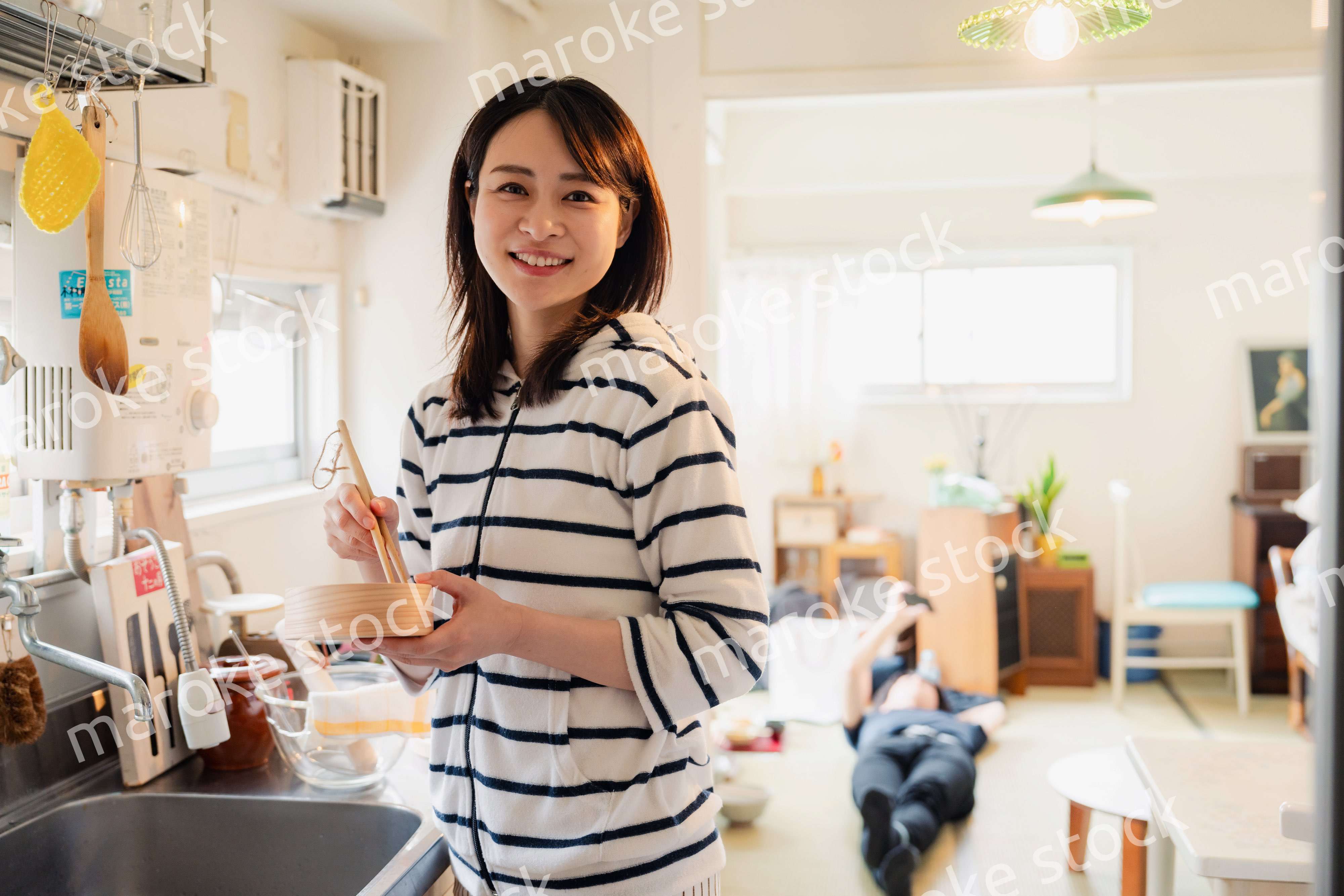 妻がお弁当を作っている後ろで寝転ぶ夫