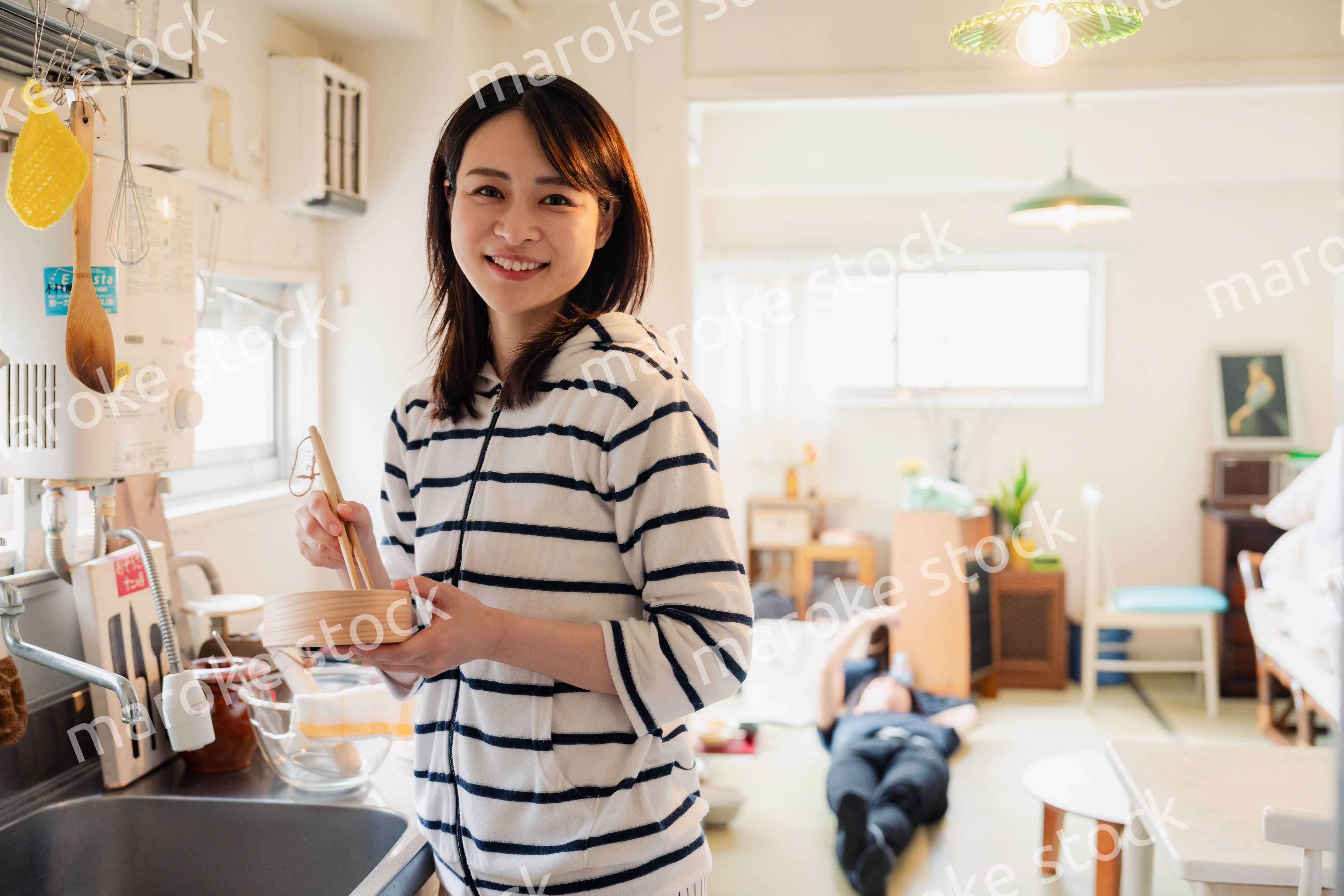 妻がお弁当を作っている後ろで寝転ぶ夫