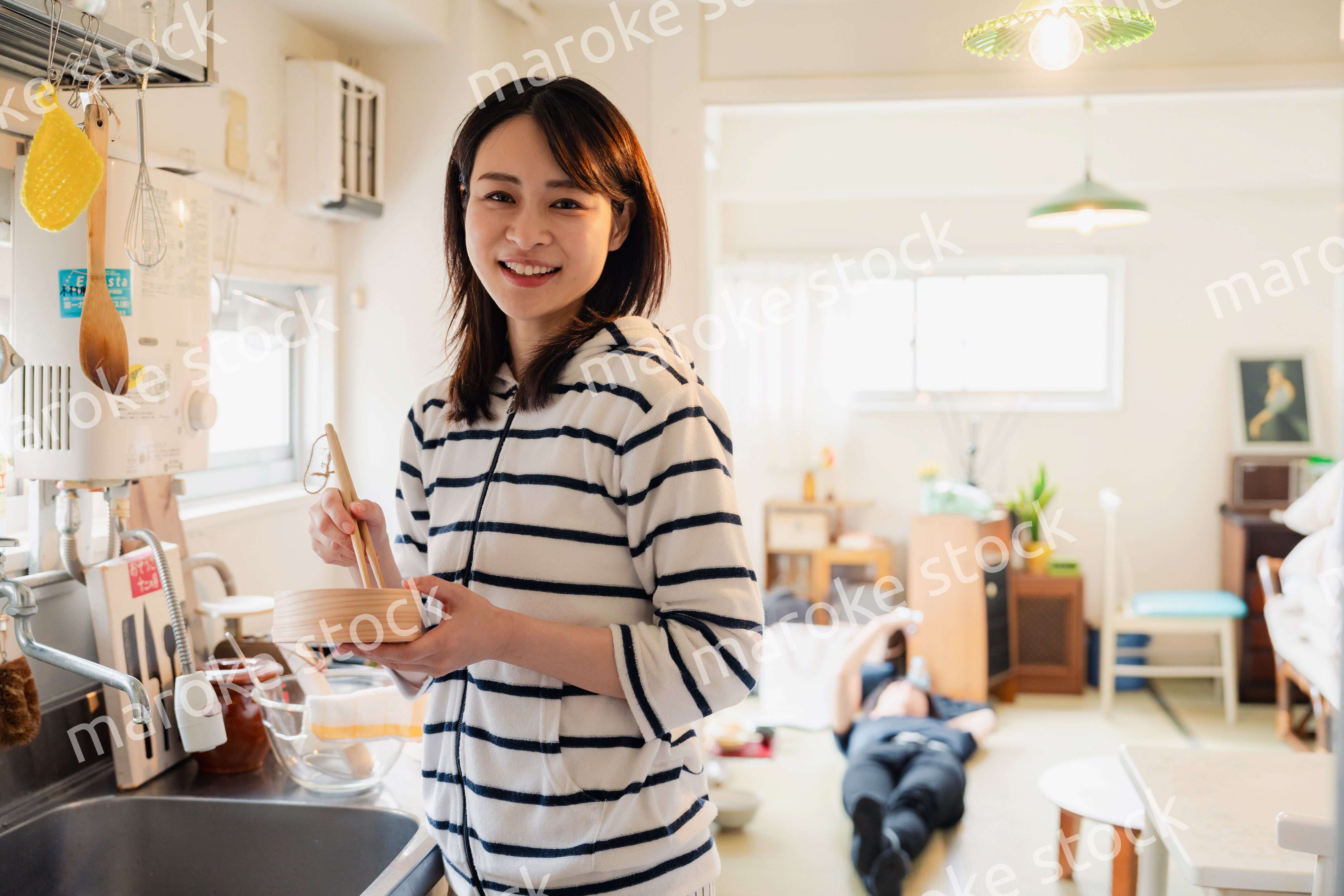 妻がお弁当を作っている後ろで寝転ぶ夫