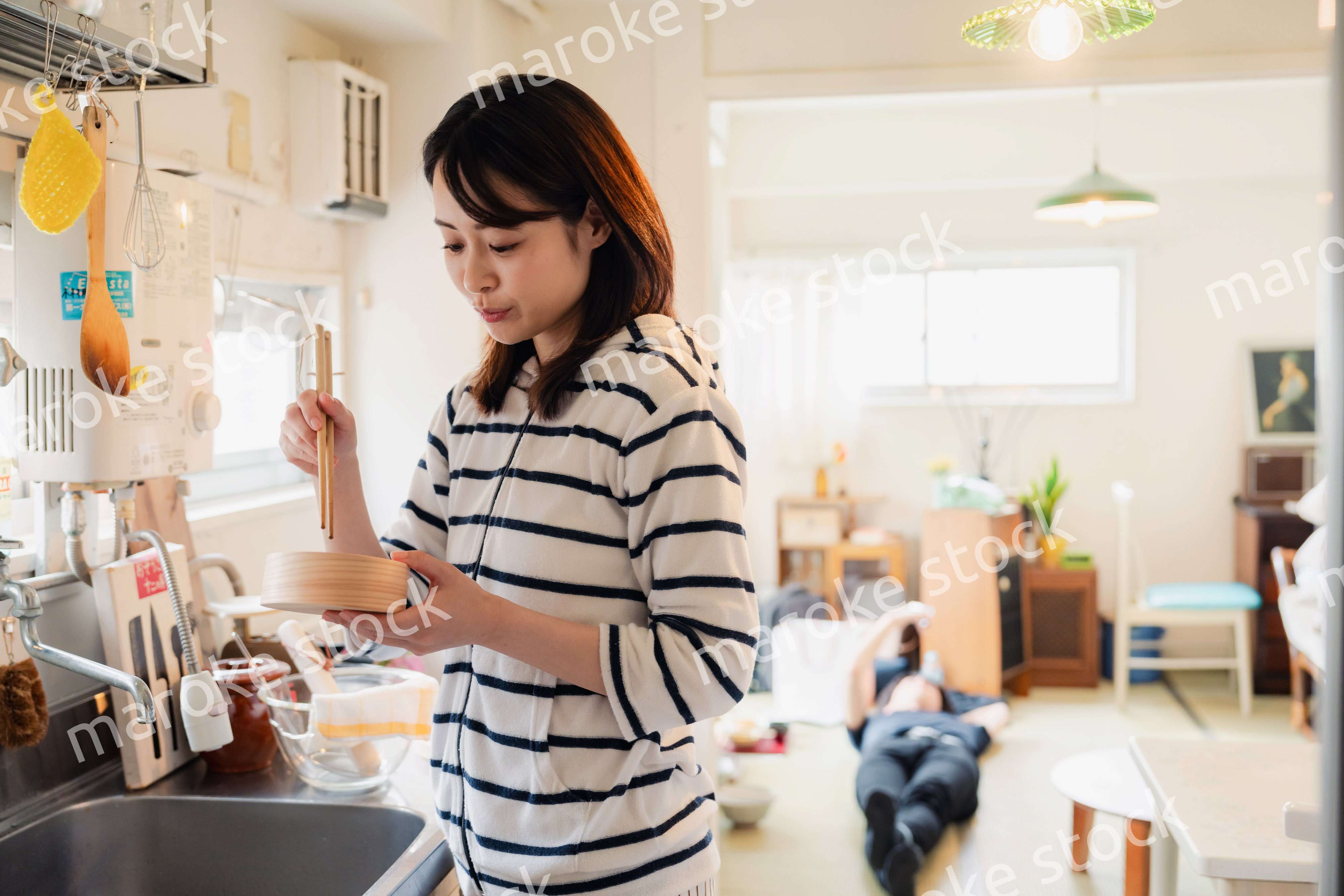 妻がお弁当を作っている後ろで寝転ぶ夫