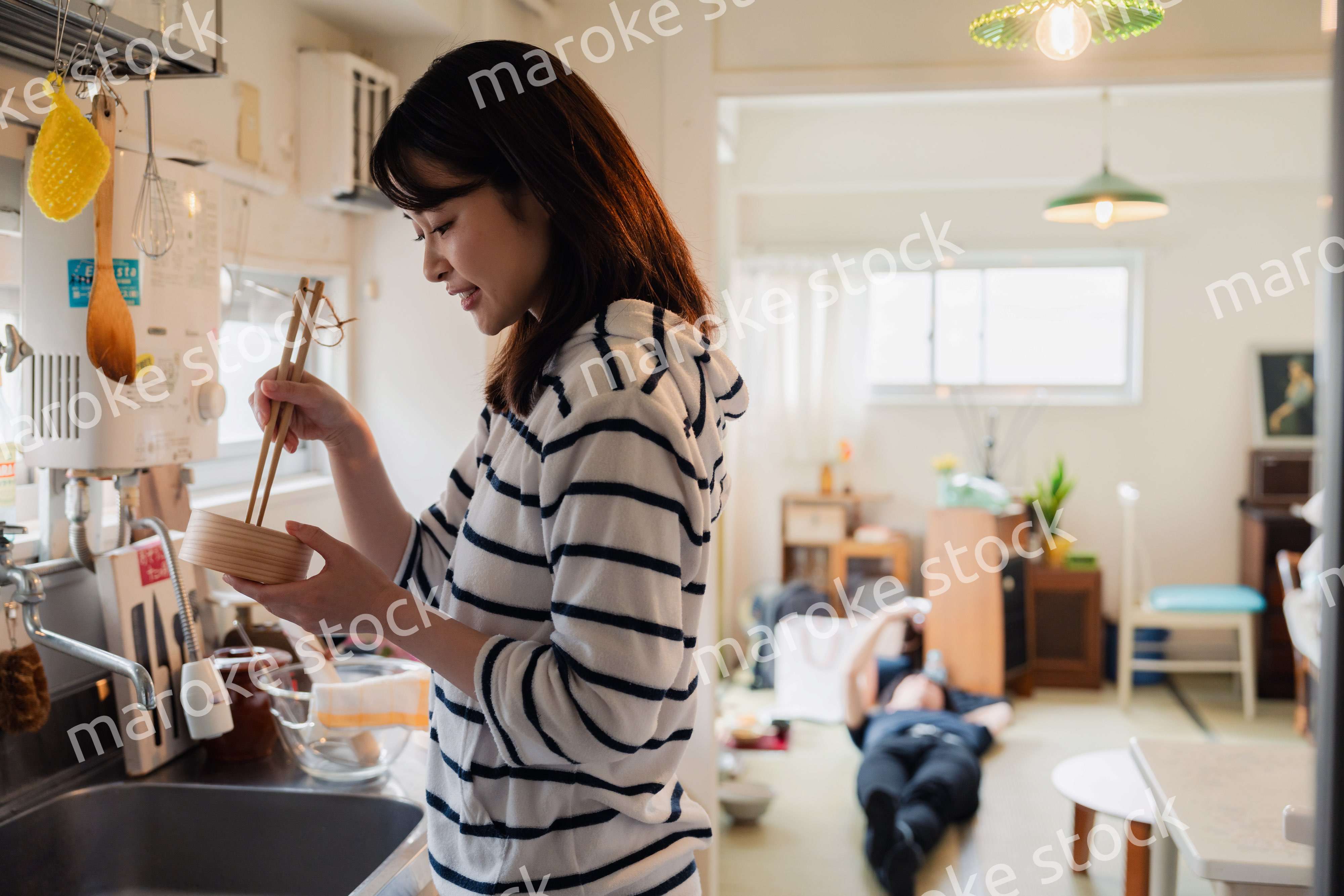 妻がお弁当を作っている後ろで寝転ぶ夫