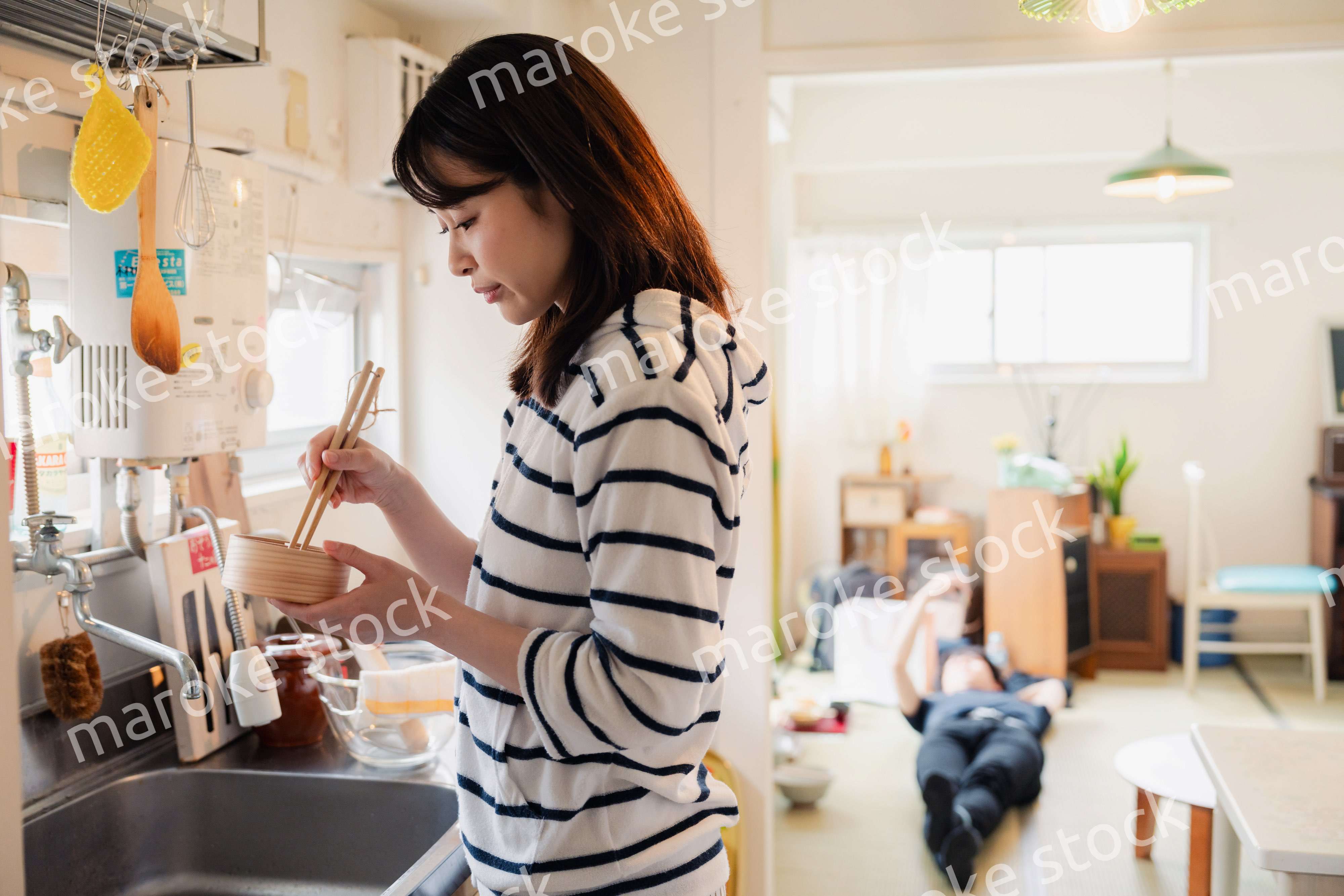 妻がお弁当を作っている後ろで寝転ぶ夫