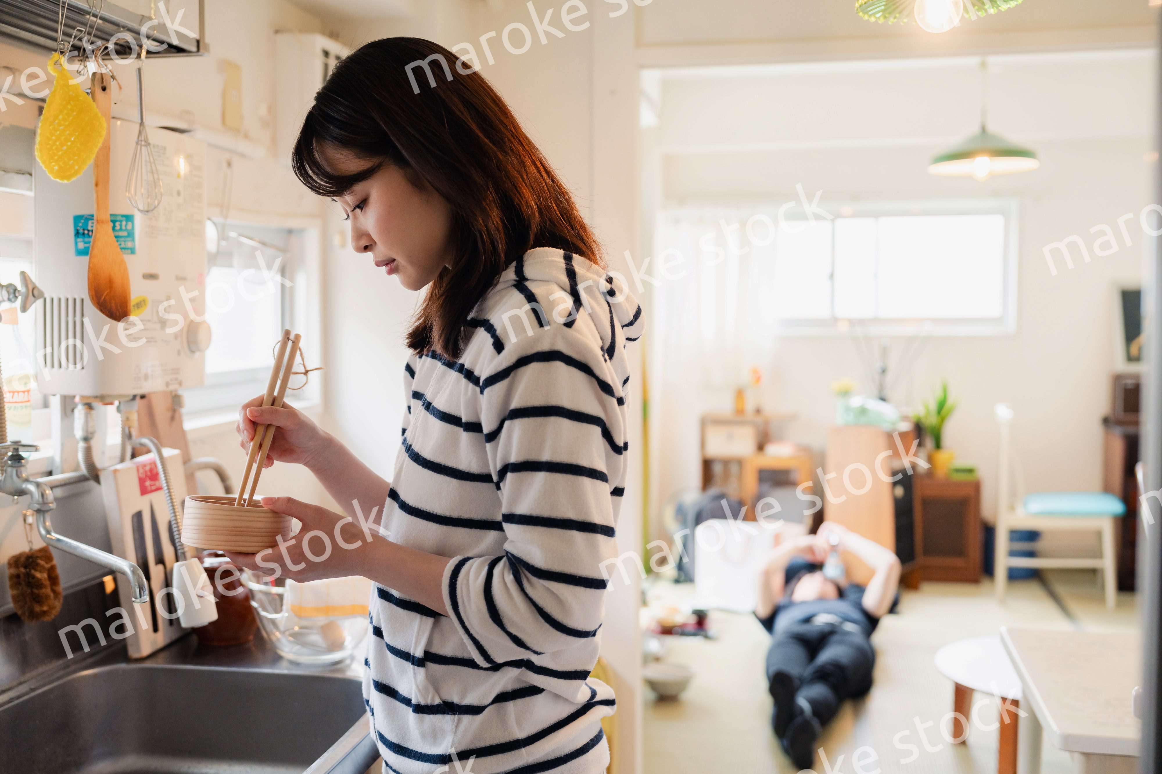 妻がお弁当を作っている後ろで寝転ぶ夫