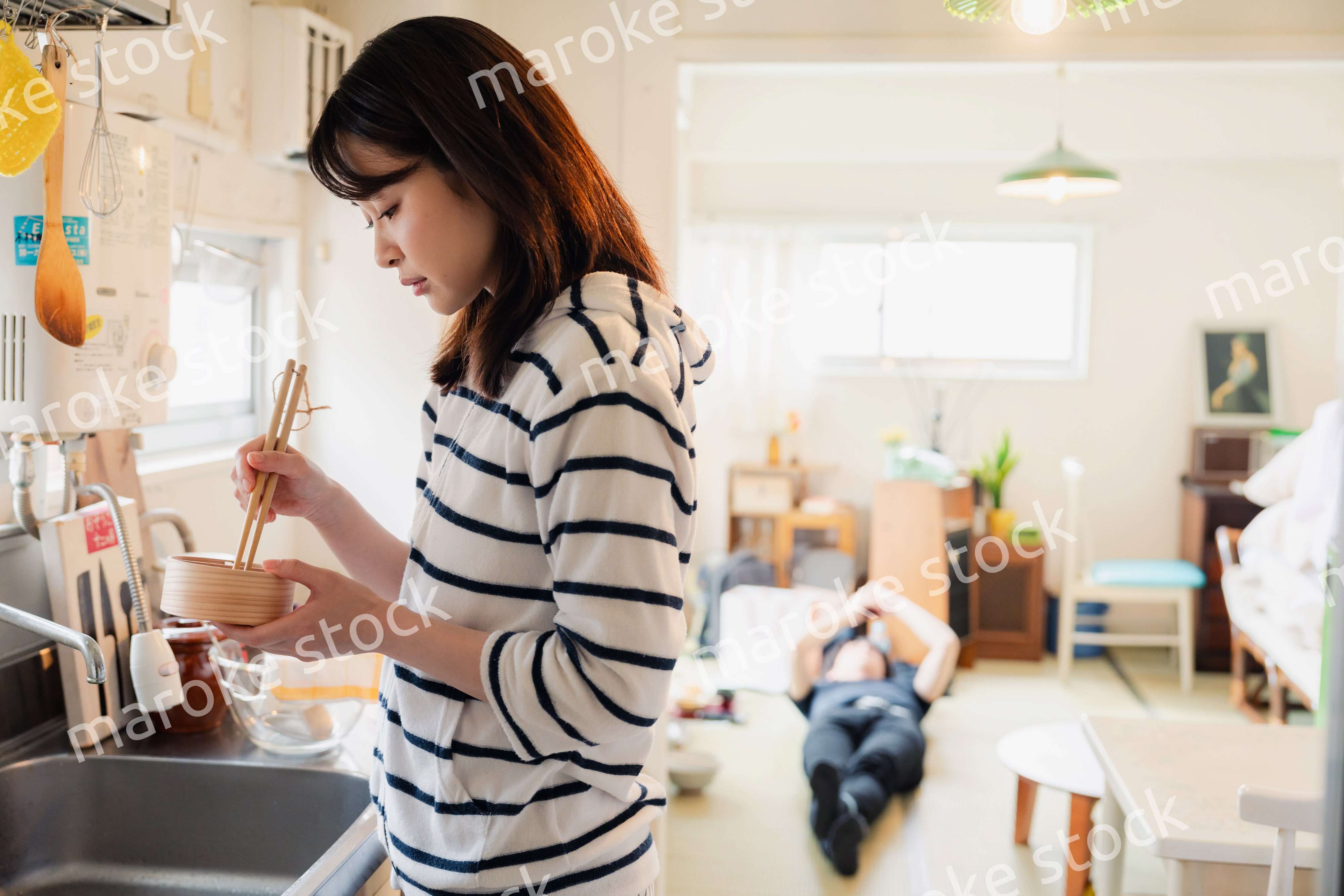 妻がお弁当を作っている後ろで寝転ぶ夫