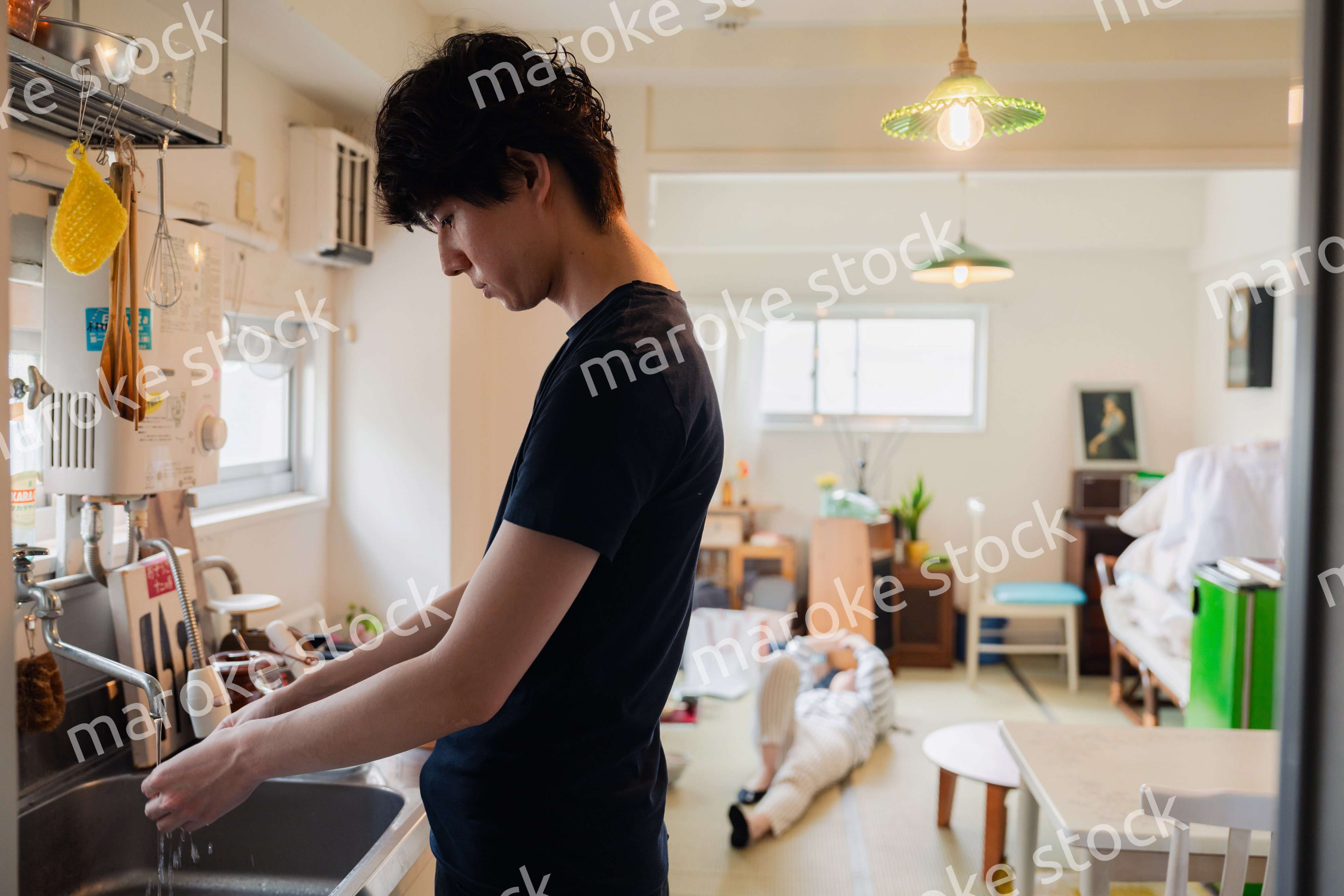 家事をする夫と後ろでサボる妻