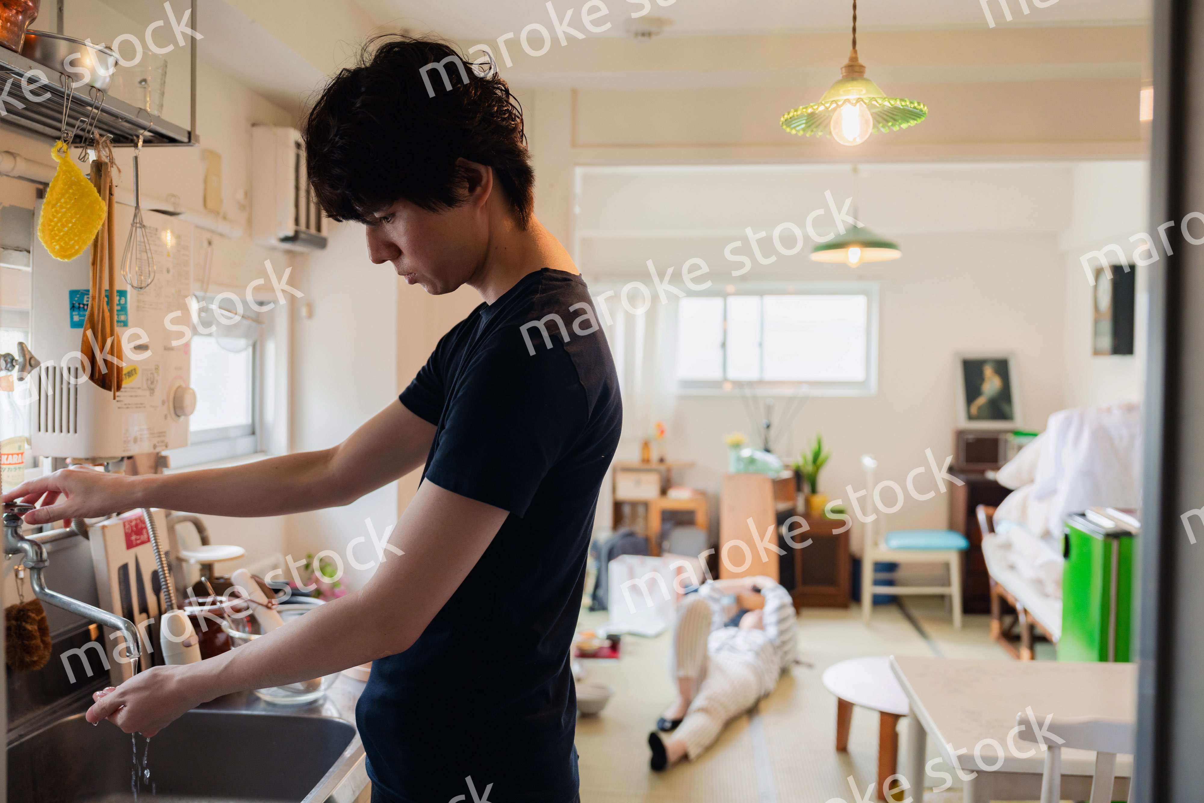 家事をする夫と後ろでサボる妻