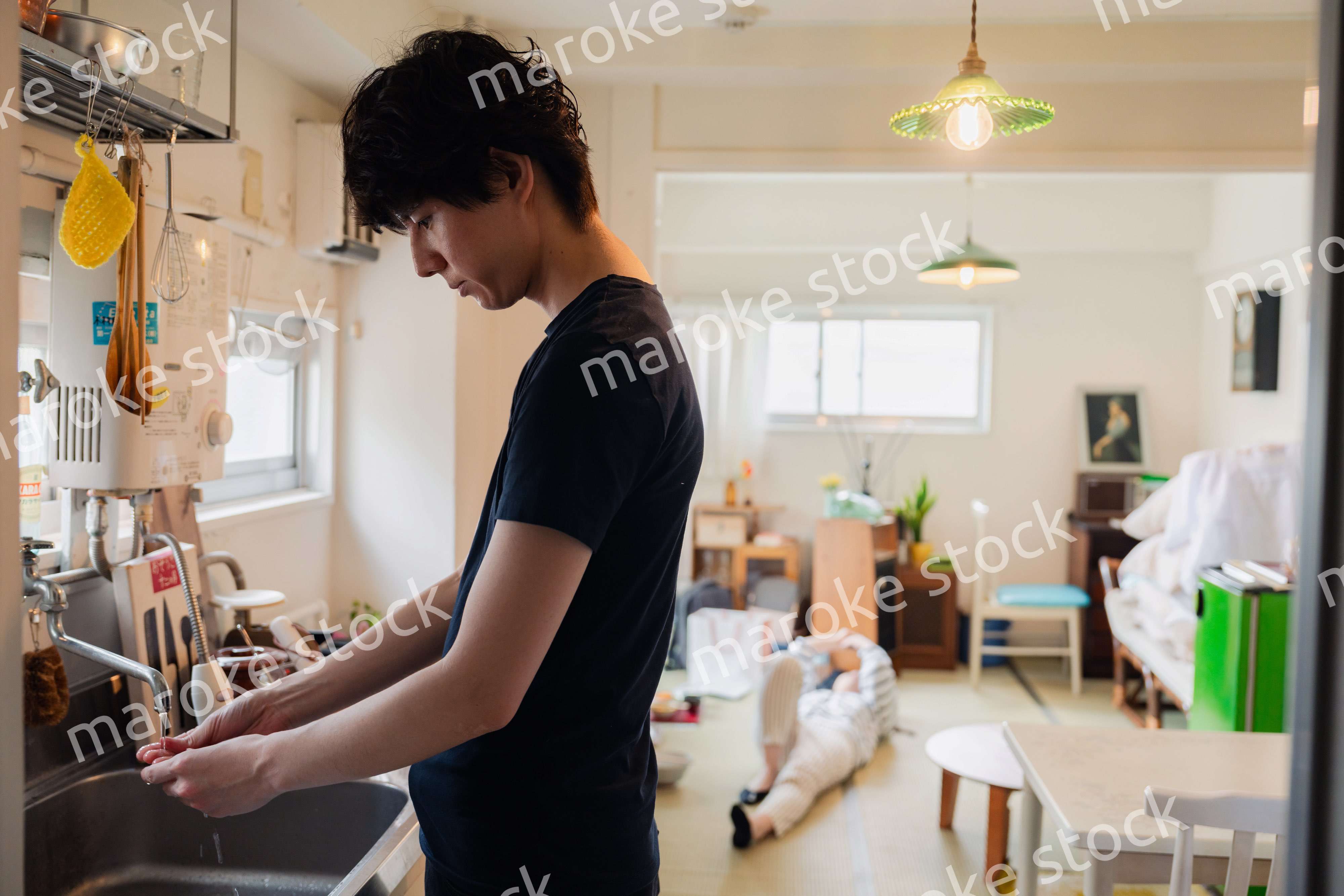 家事をする夫と後ろでサボる妻