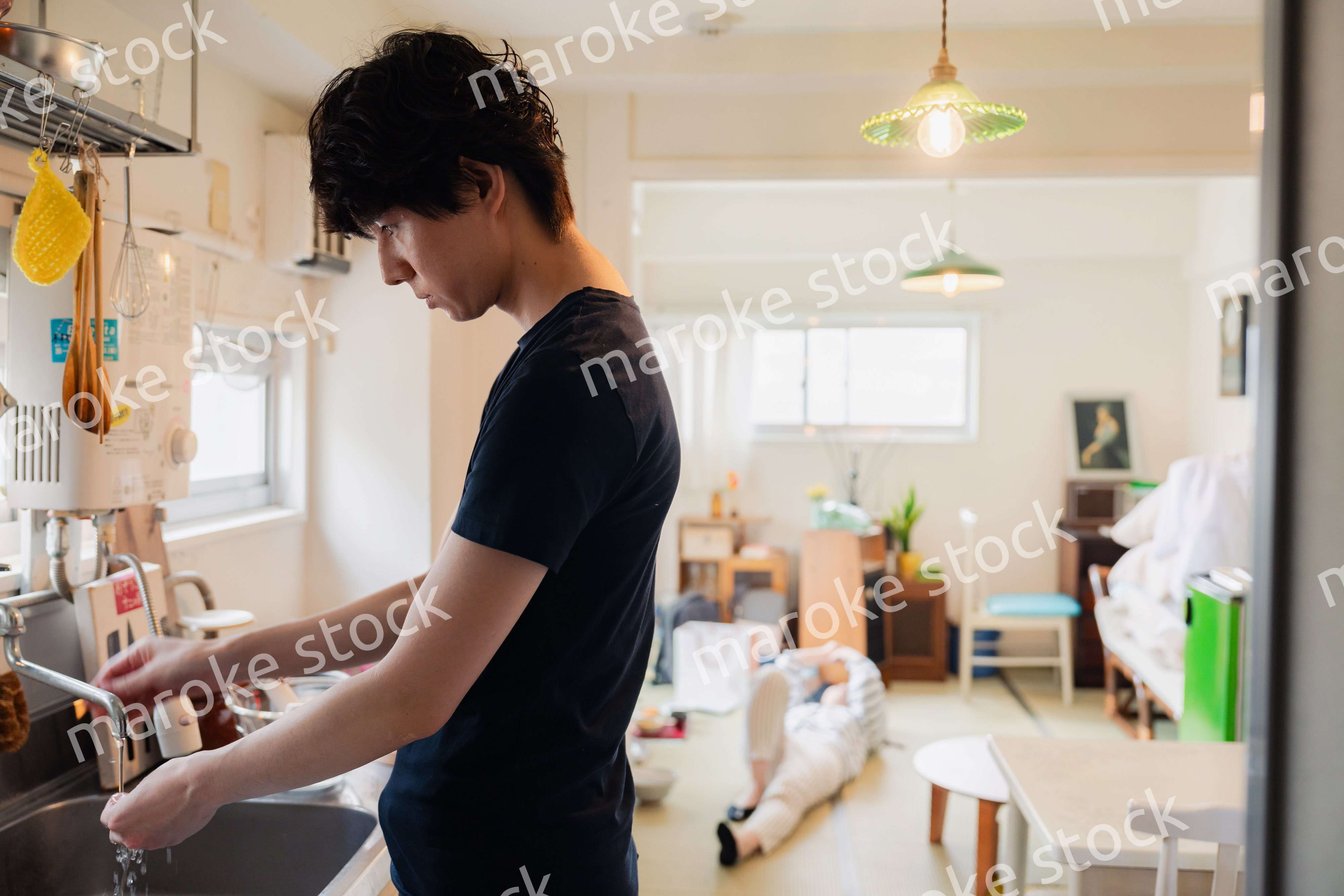 家事をする夫と後ろでサボる妻