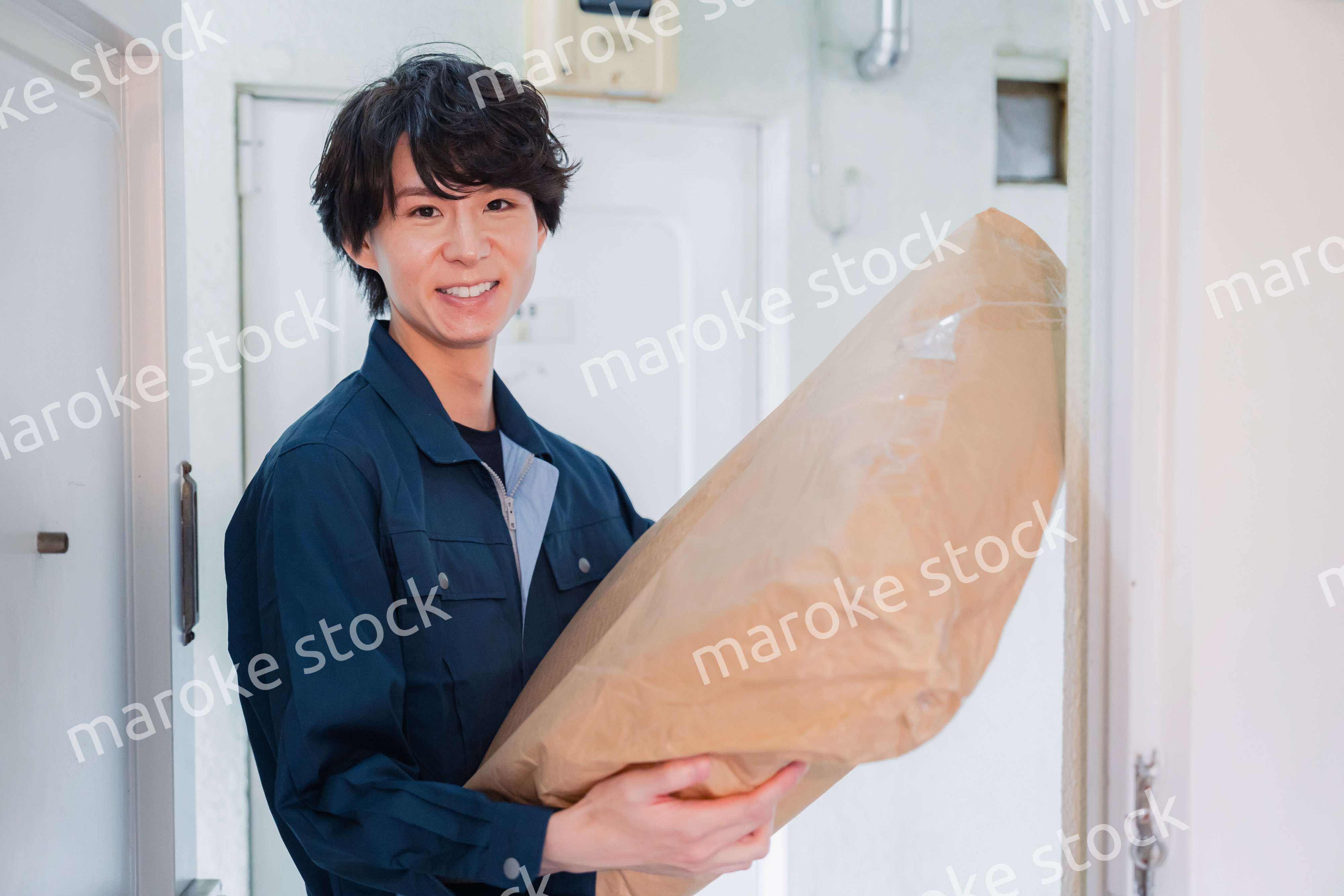 古いマンションに荷物を届ける男性