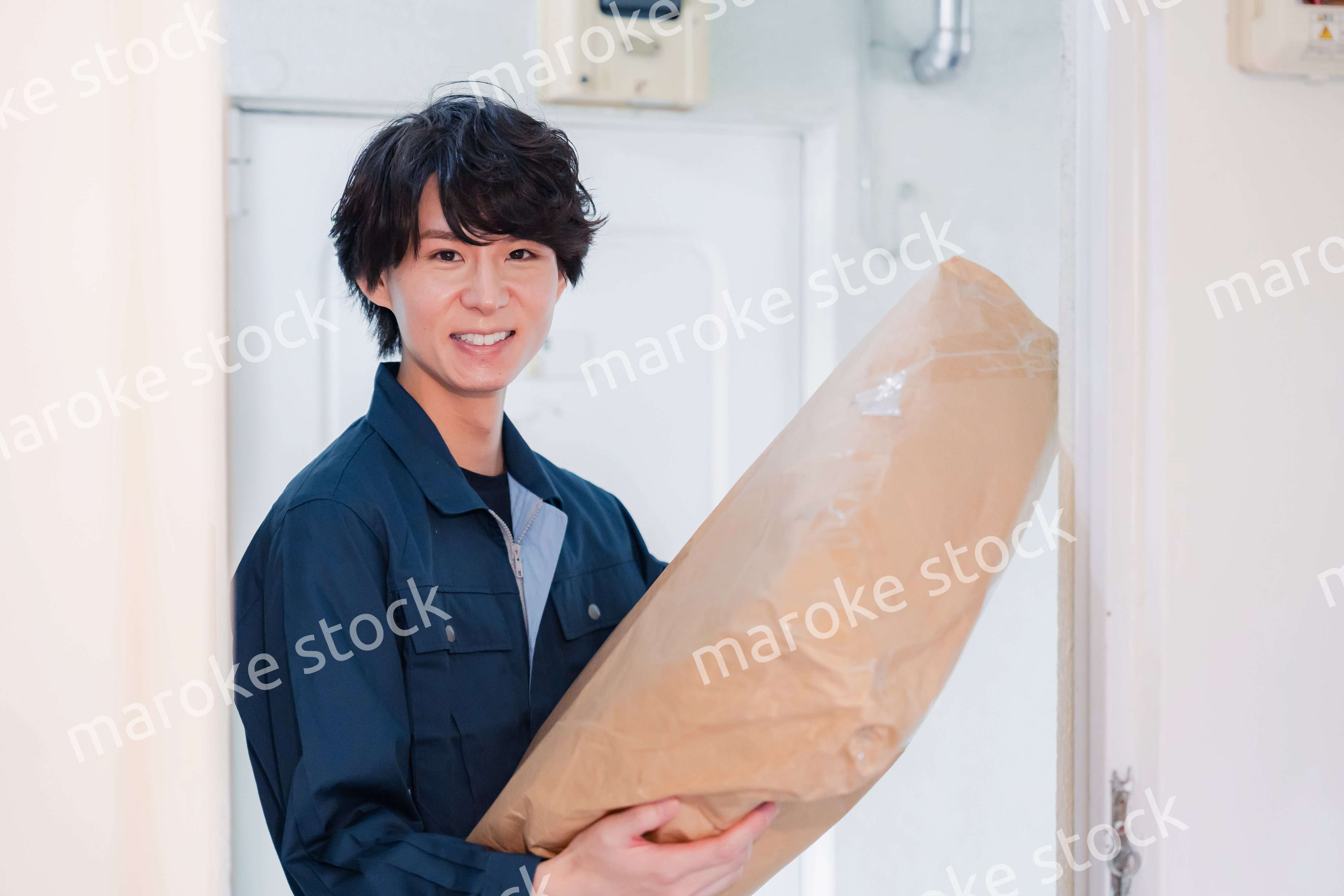 古いマンションに荷物を届ける男性