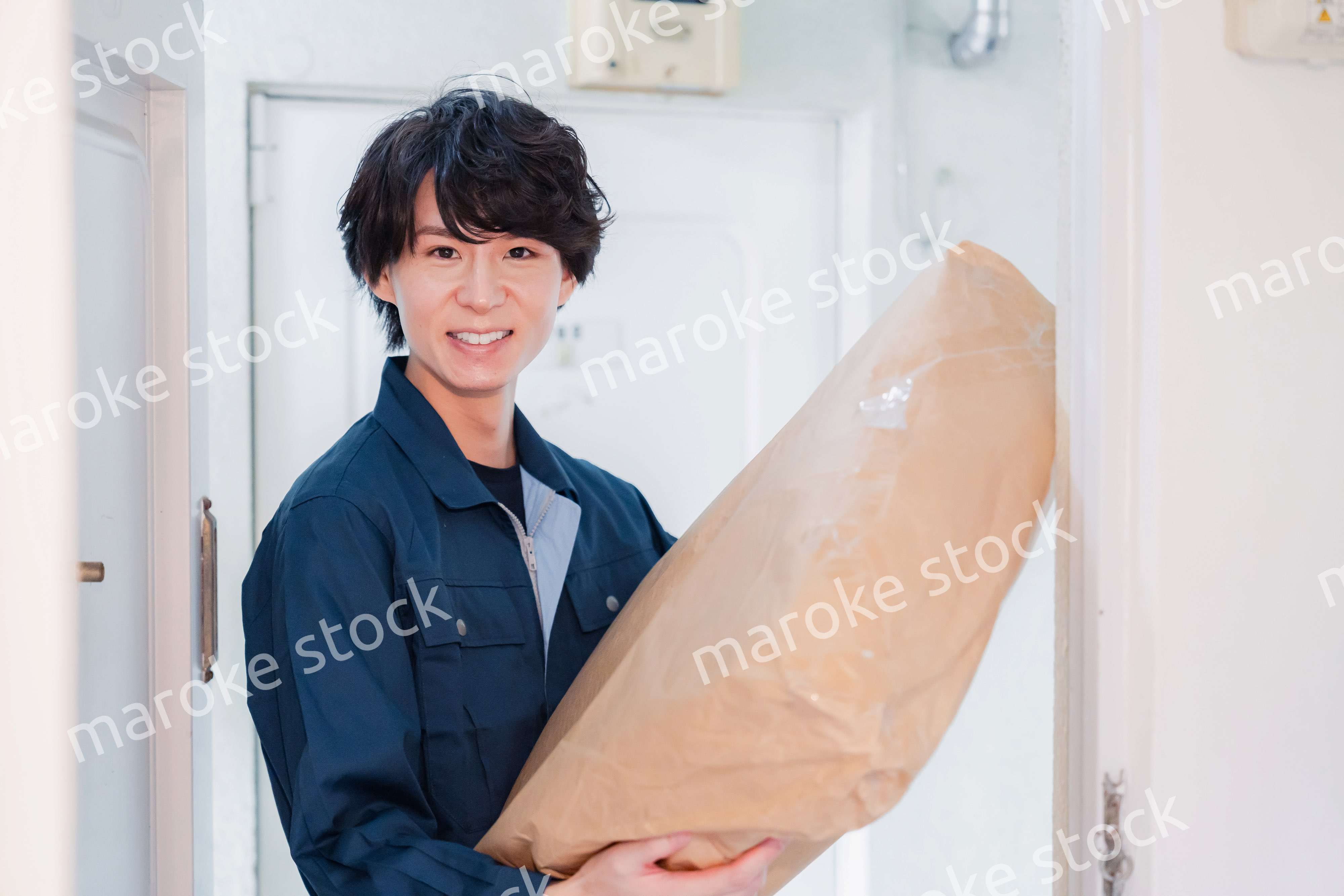 古いマンションに荷物を届ける男性