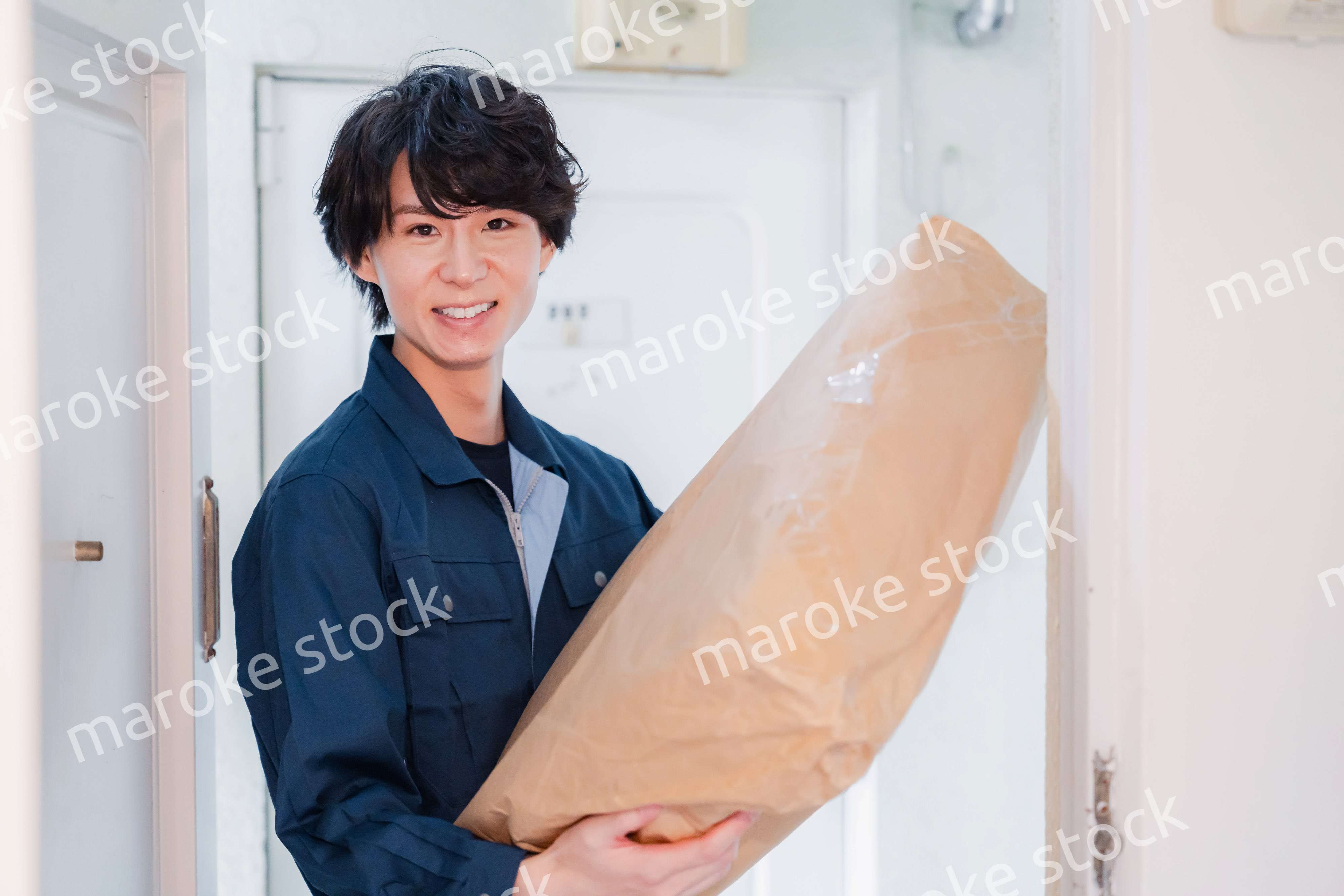 古いマンションに荷物を届ける男性